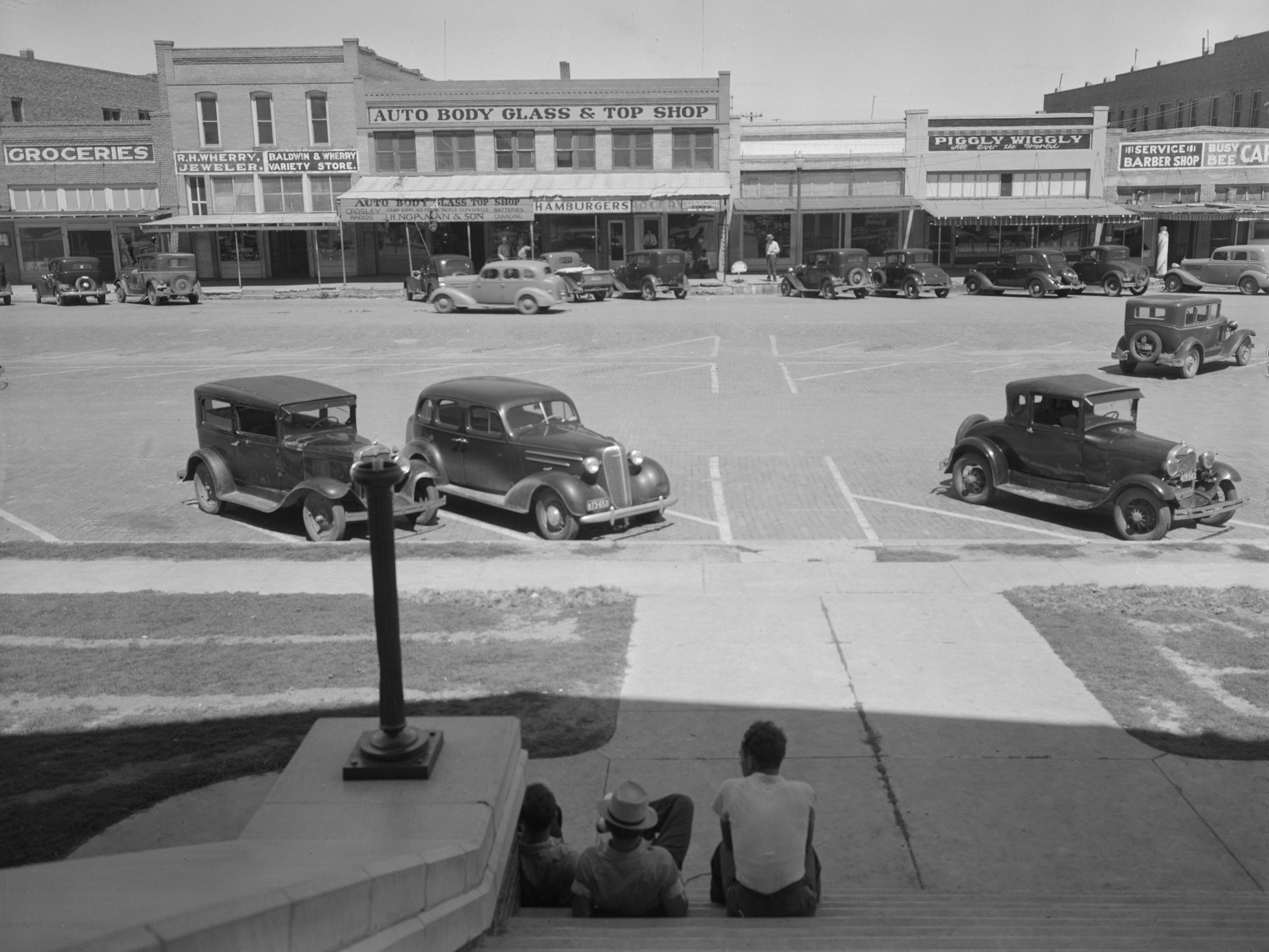 A street with cars parked along it in front of a Piggly Wiggly
