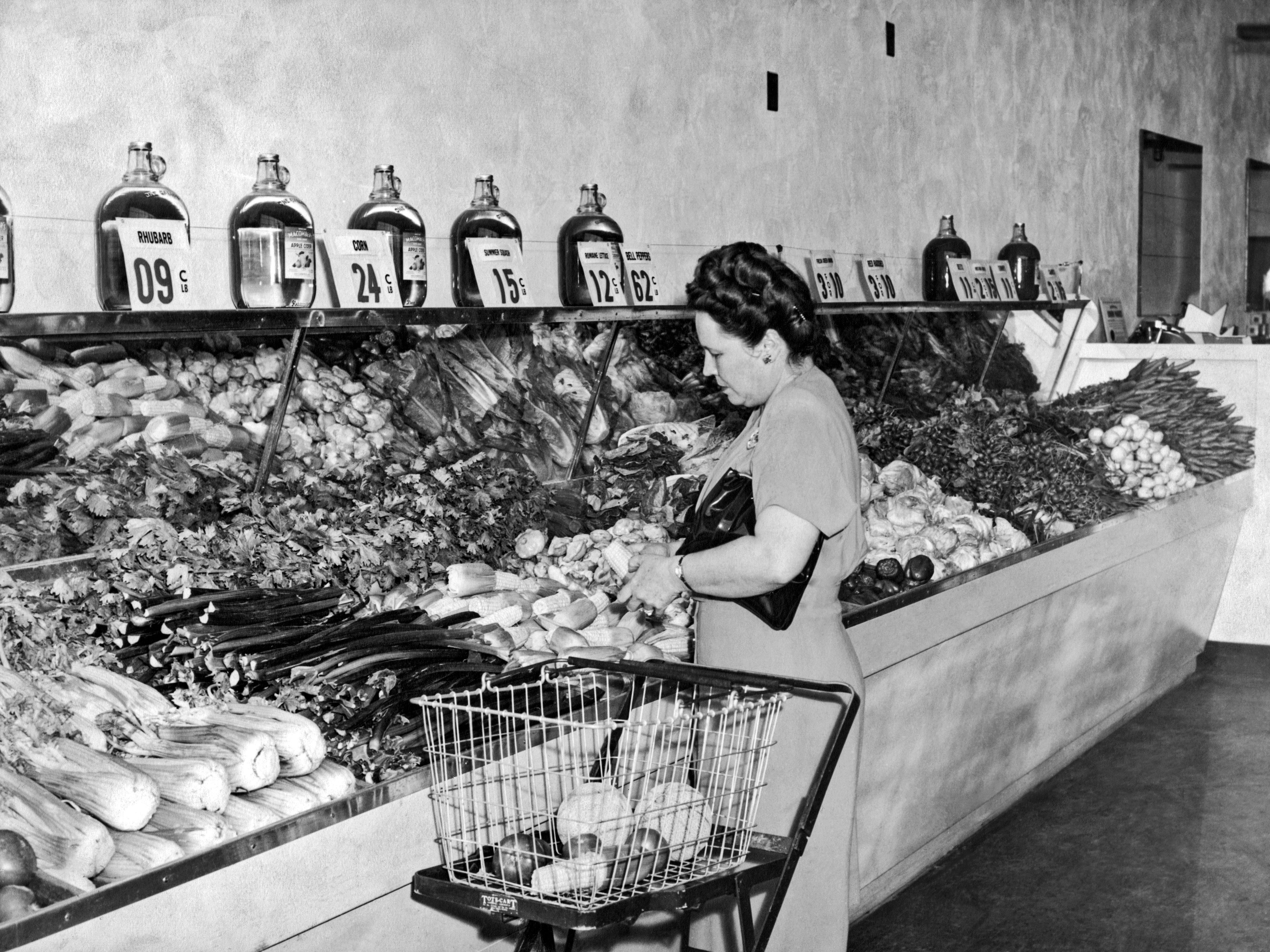 A woman looks at produce to load in a shopping cart