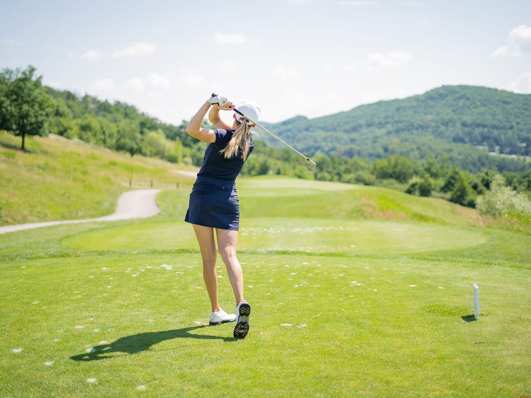 A woman teeing off at a golf course.
