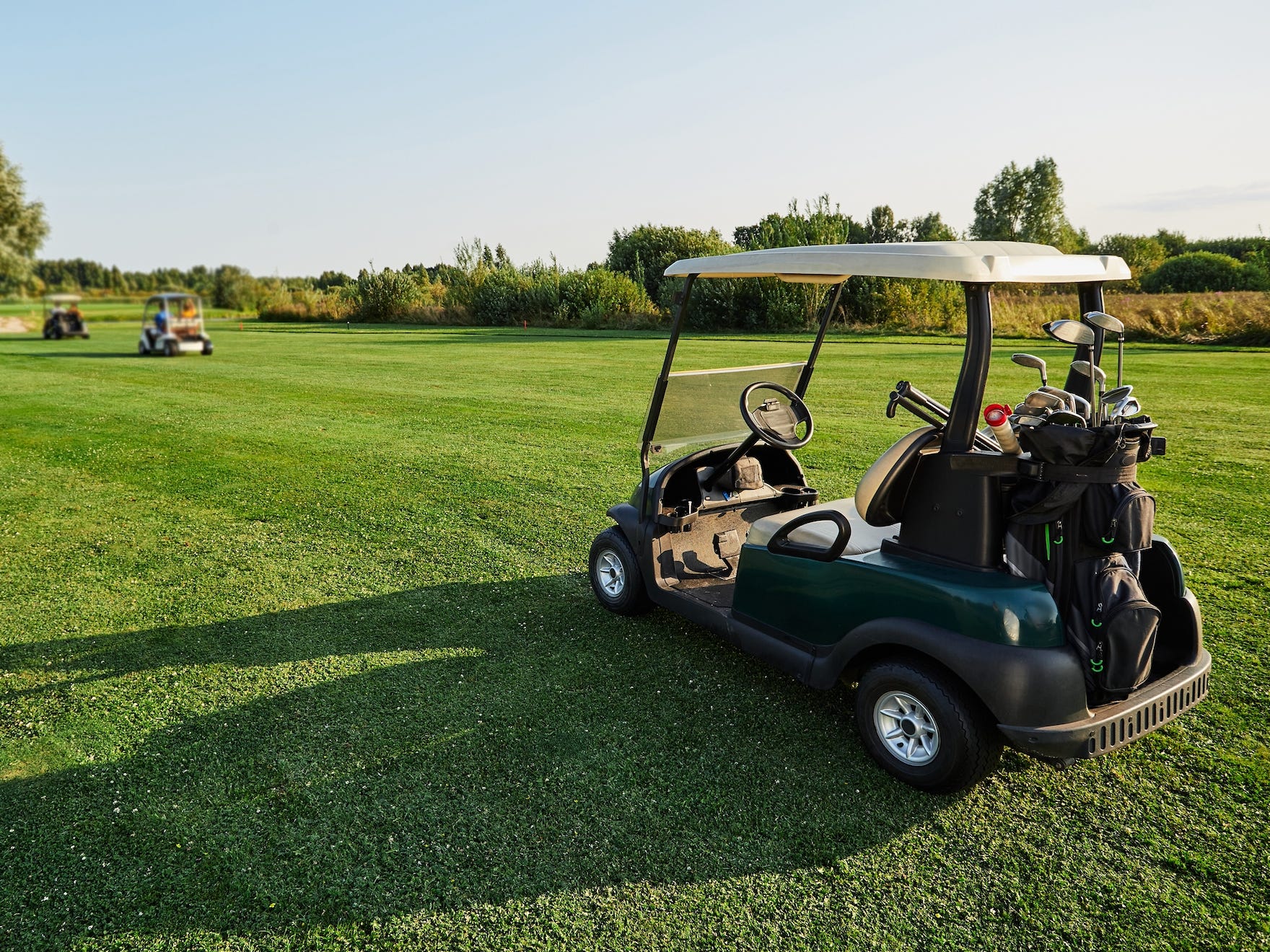 Golf carts lined up on a golf course.