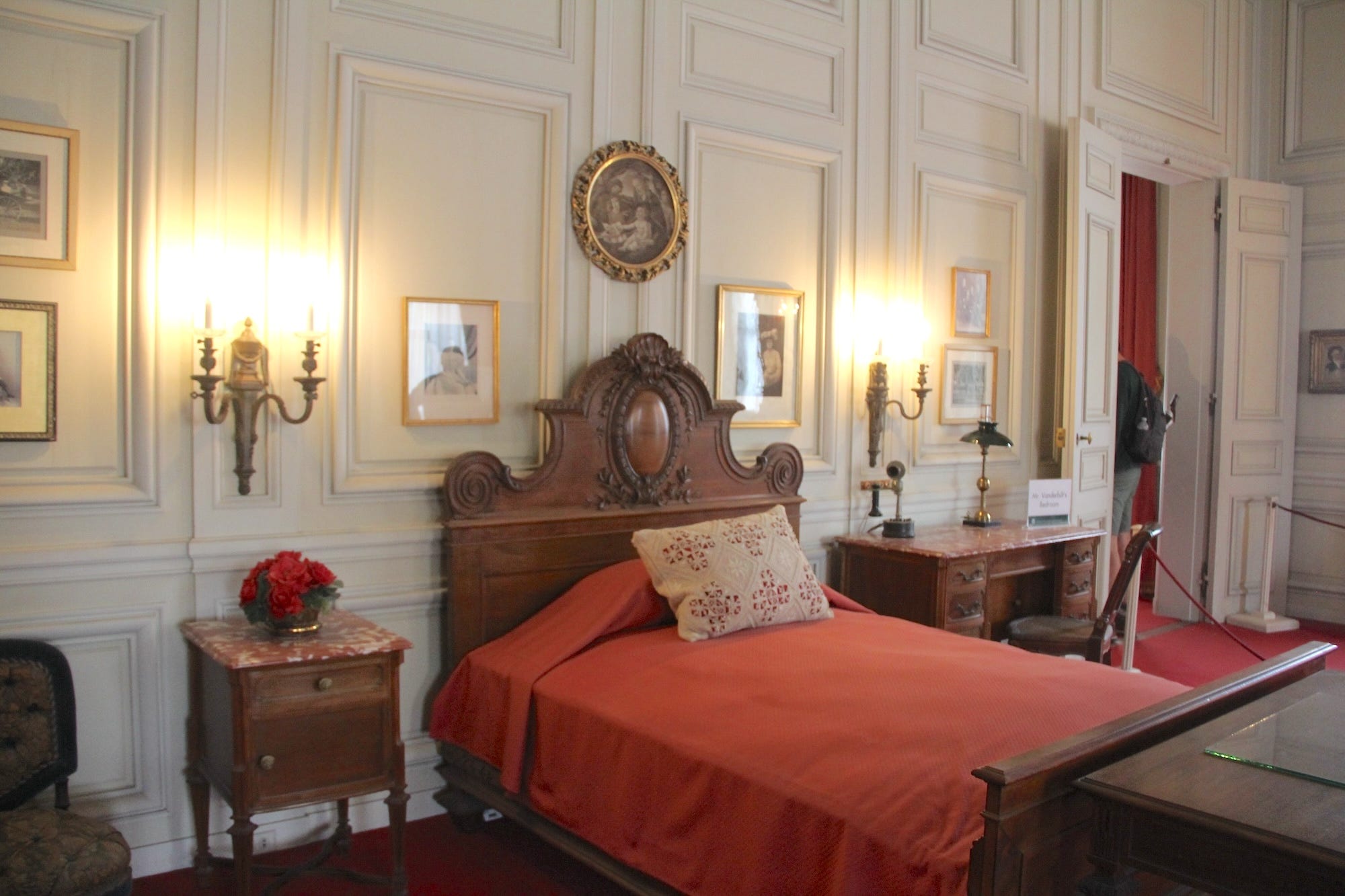 Vanderbilt's bedroom in The Breakers with a wood bed with red blankets.