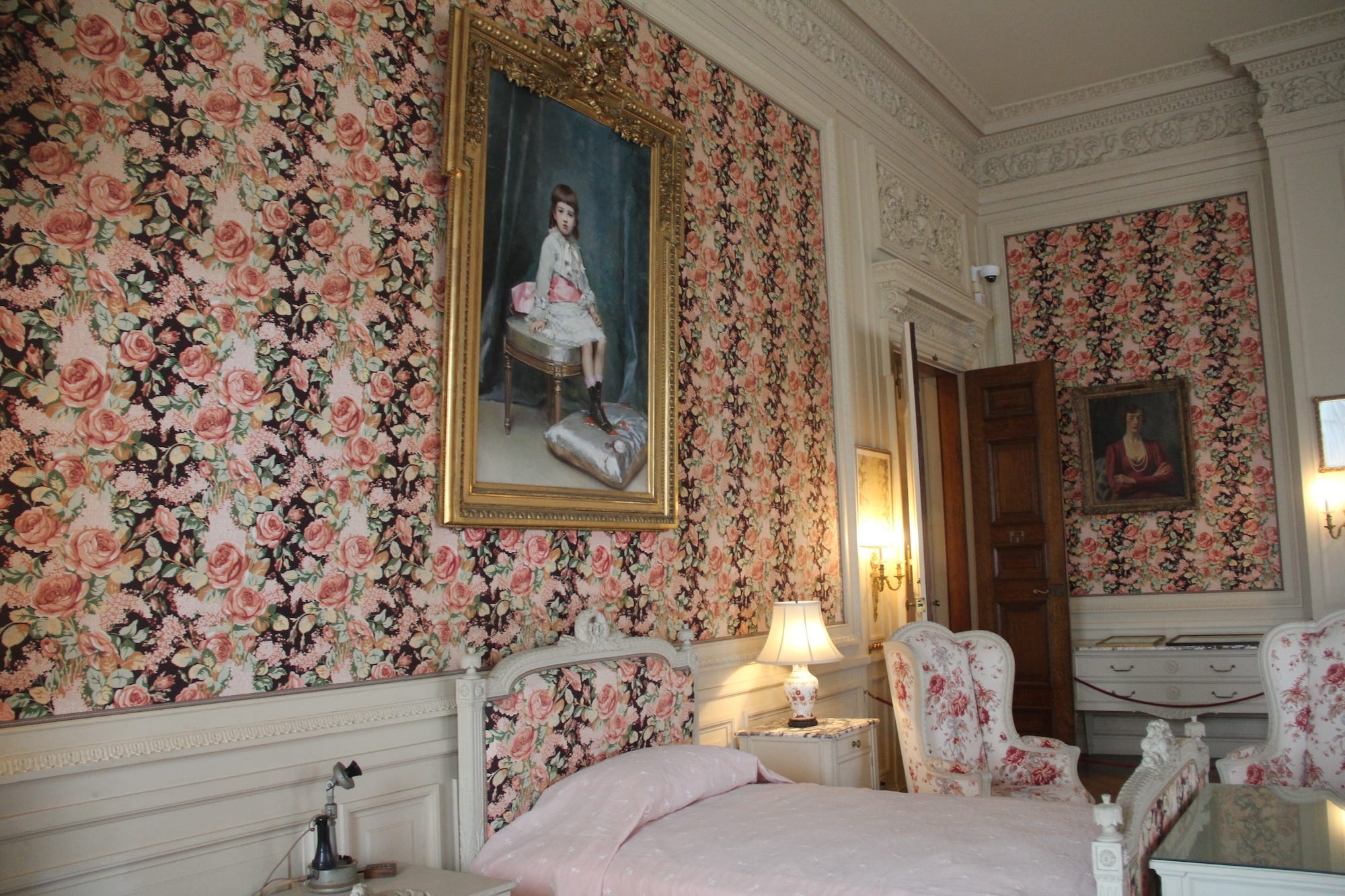 A bedroom with pink floral wallpaper at The Breakers.