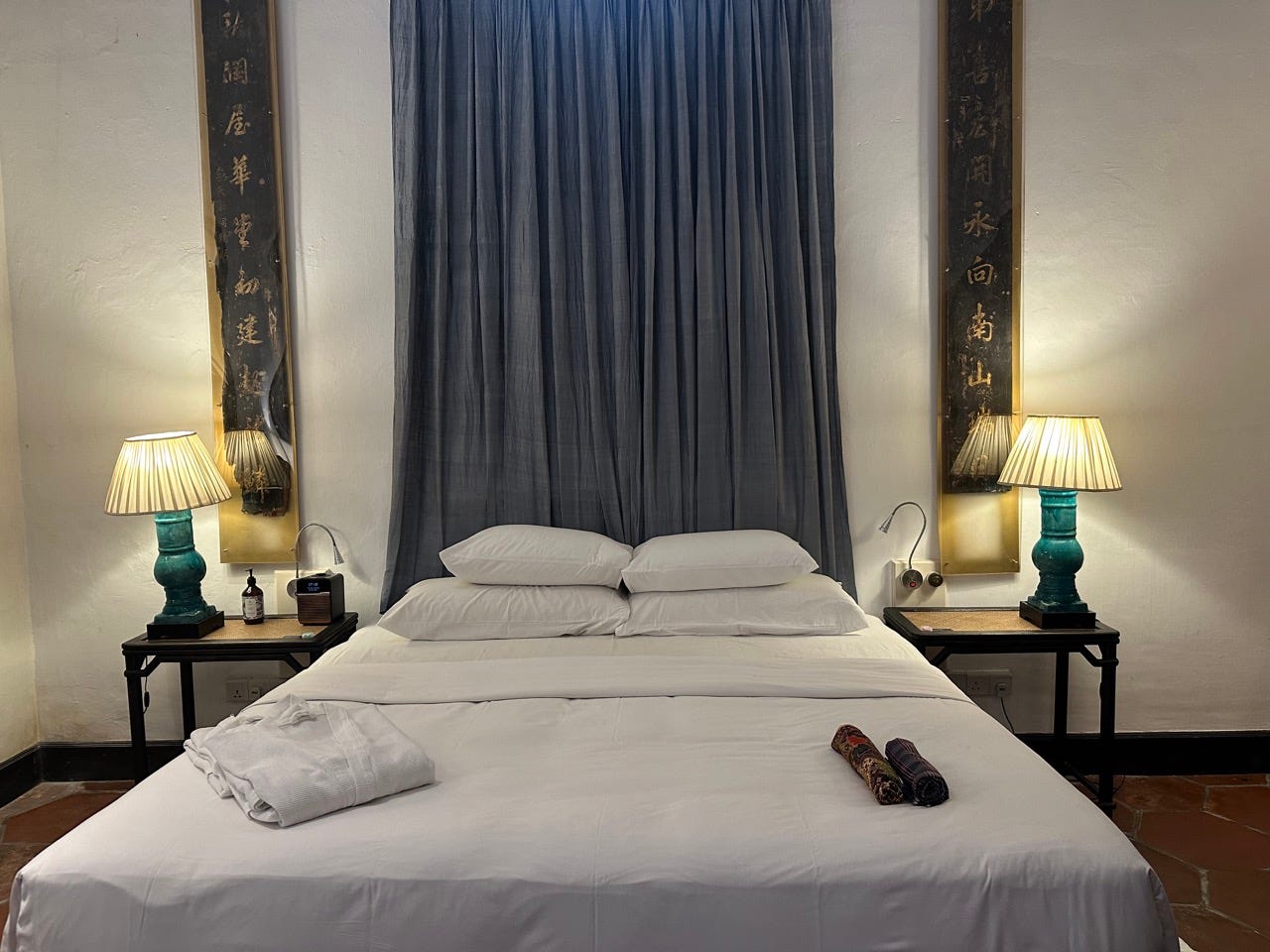 White bed in hotel room with lamp on nightstand on either side of bed