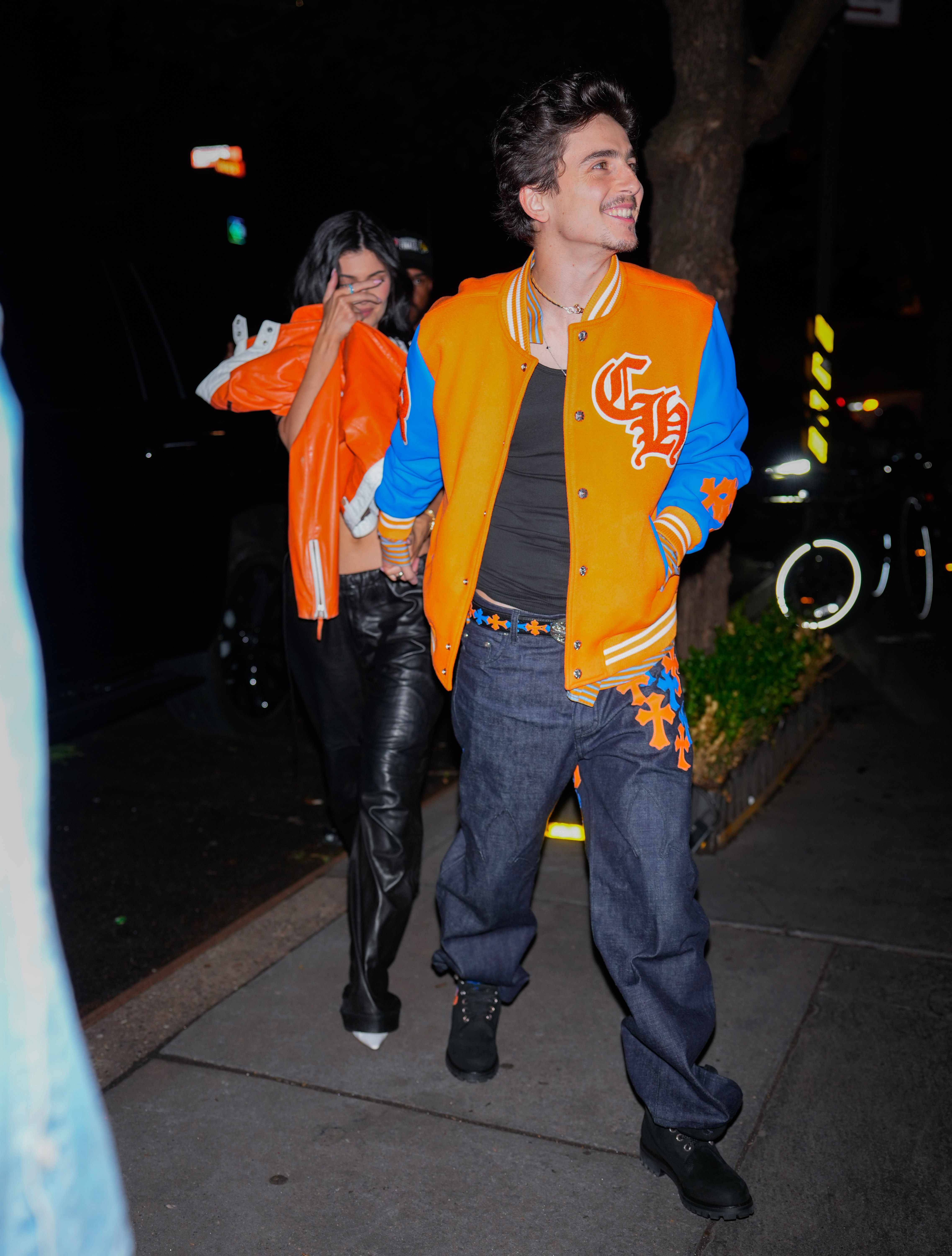 Kylie Jenner walks in orange jackets with Timothee Chalamet. 