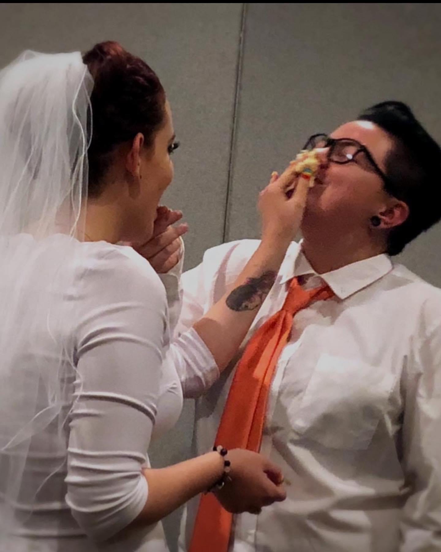 A wedding picture shows the bride shoving cake up the groom's nose.