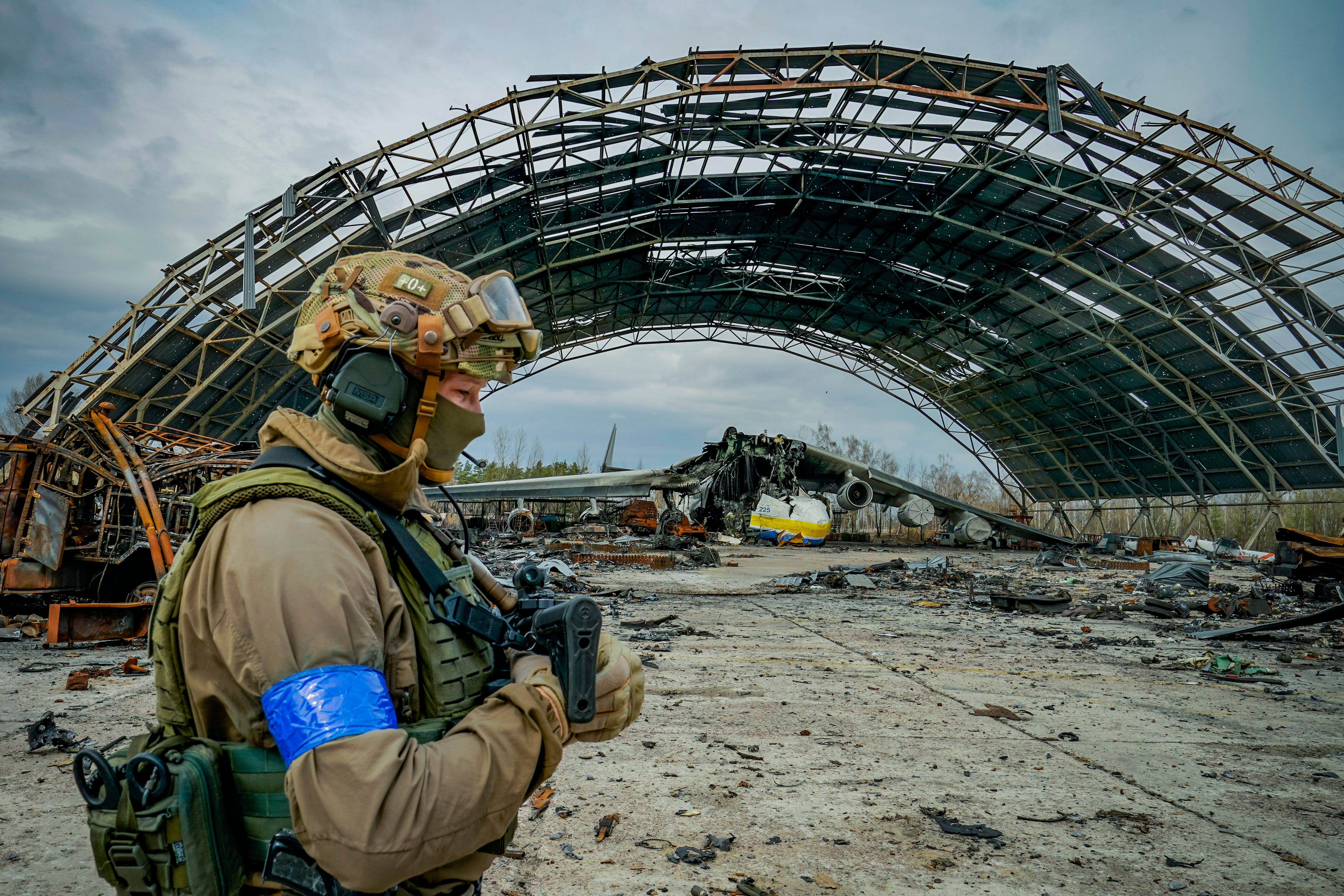 A Ukrainian soldier passes near a hangar in the Hostomel airport near Kyiv with the destroyed cargo plane Antonov An-225 Mriya.