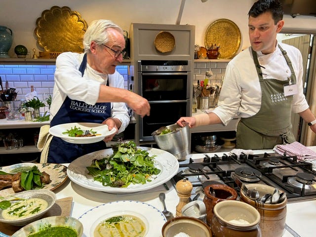 Two chefs making a big green salad.