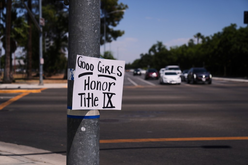 A sign is posted on a street pole outside the stadium supporting Title IX regulation.