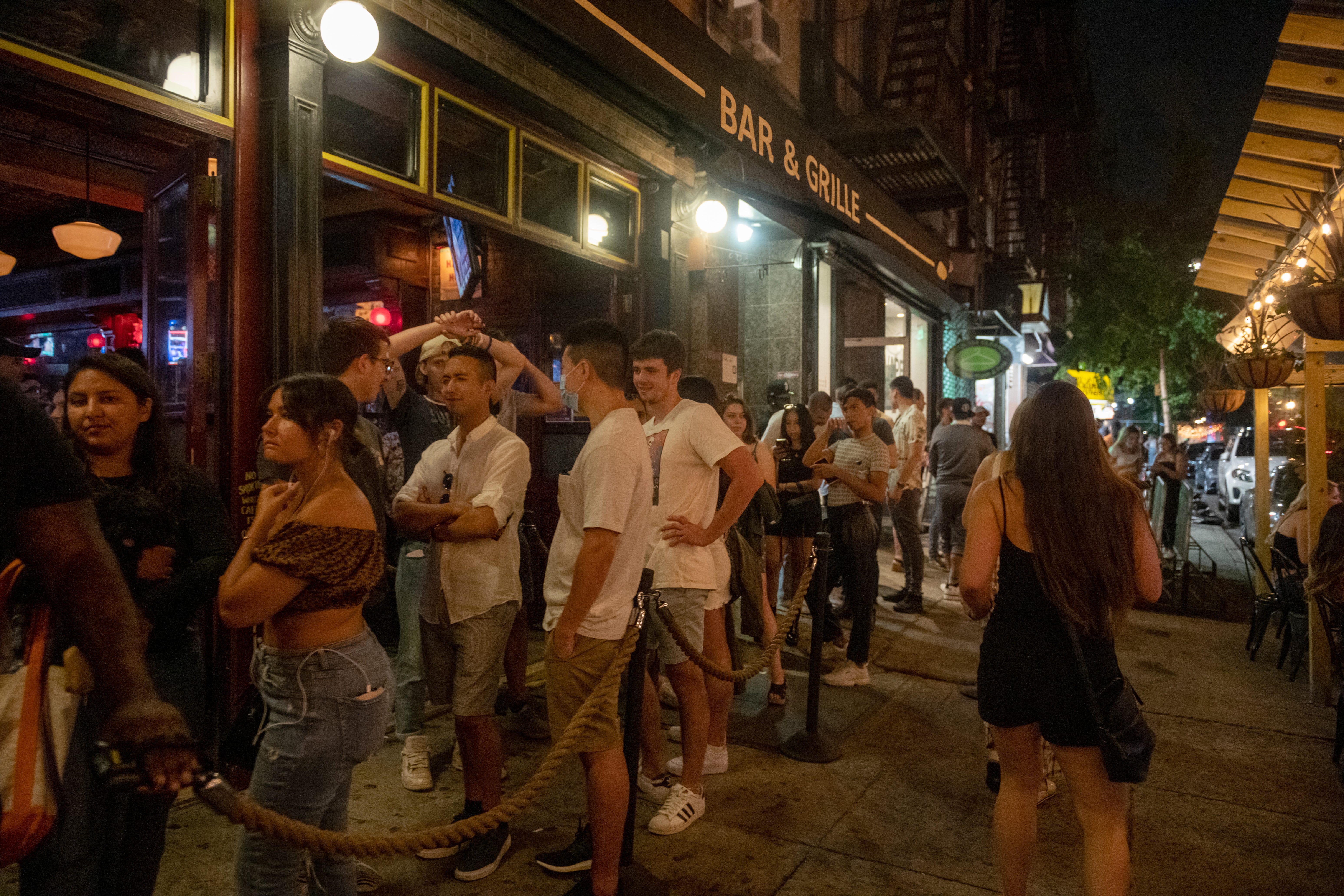 NEW YORK, NEW YORK - MAY 22: People without masks wait in line outside Hair of The Dog at night in the Lower East Side on May 22, 2021 in New York City.