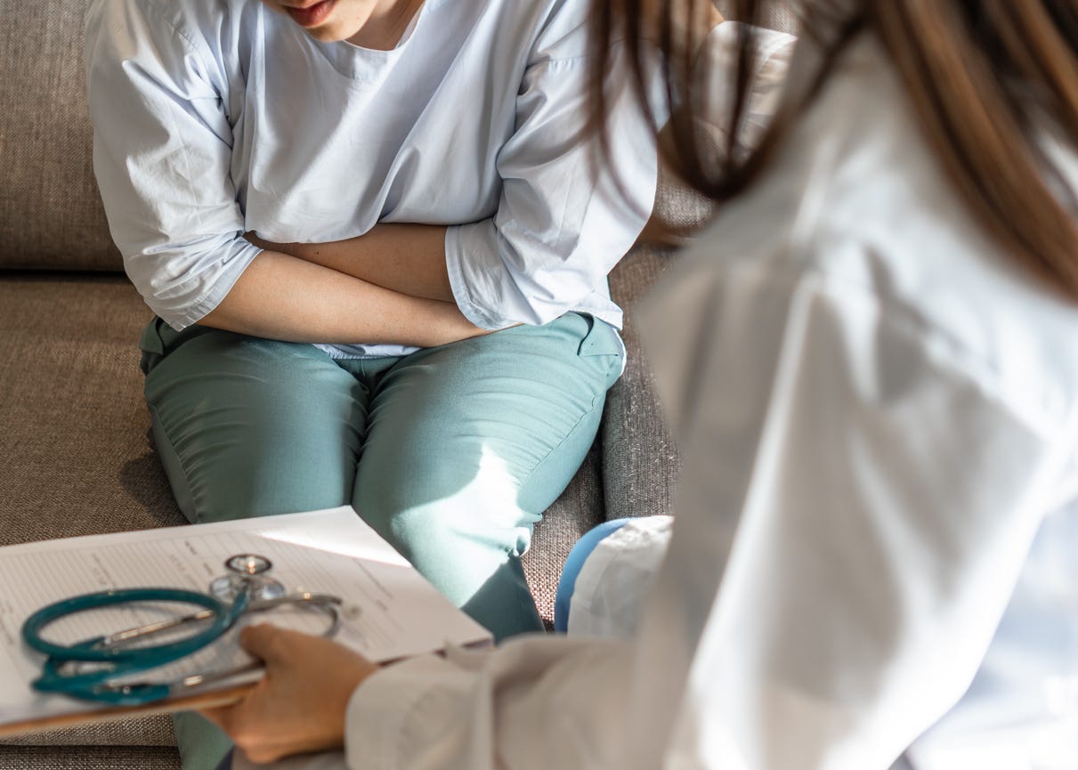 A woman holding her stomach while talking to doctor