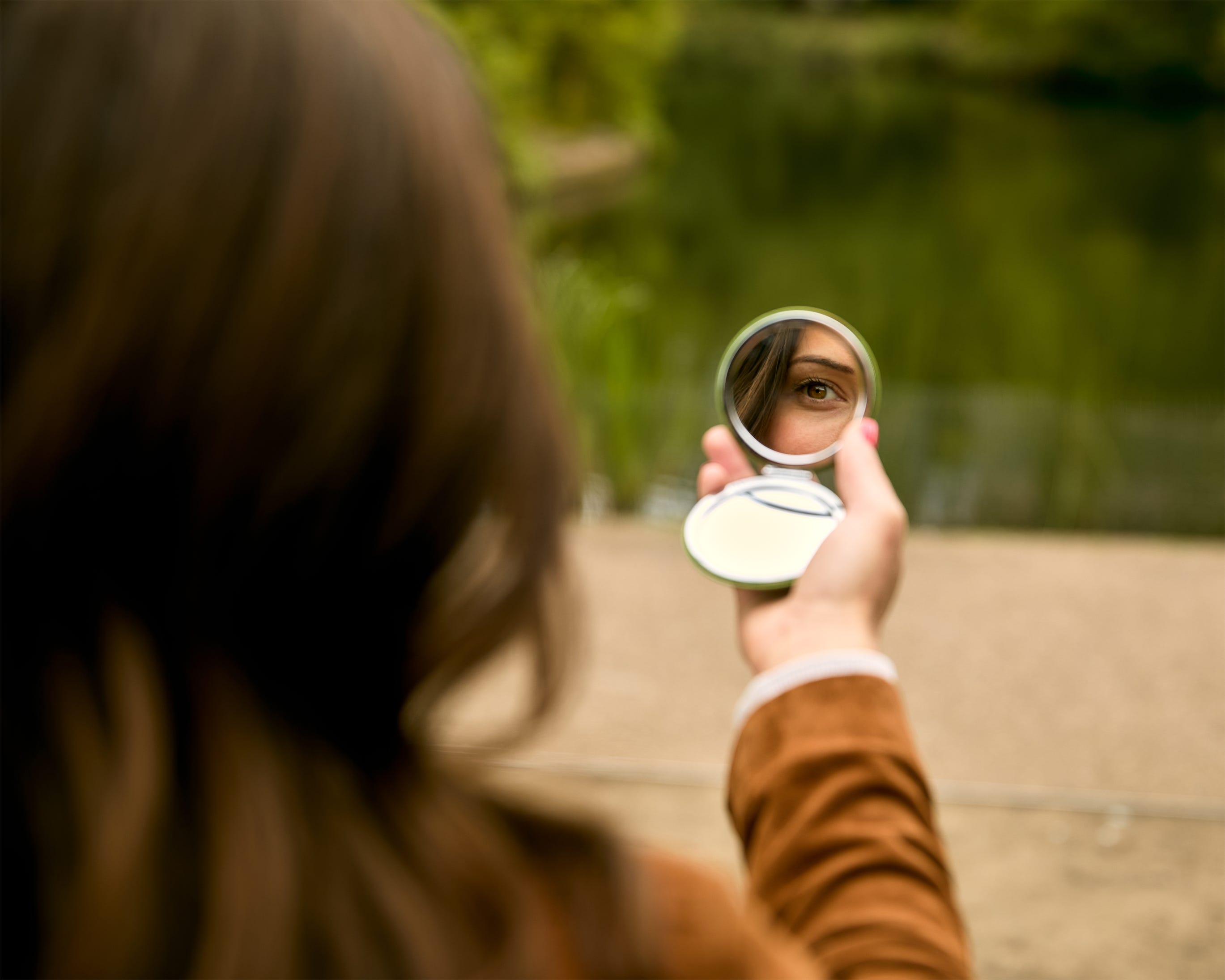 A woman looking into a compact mirror.