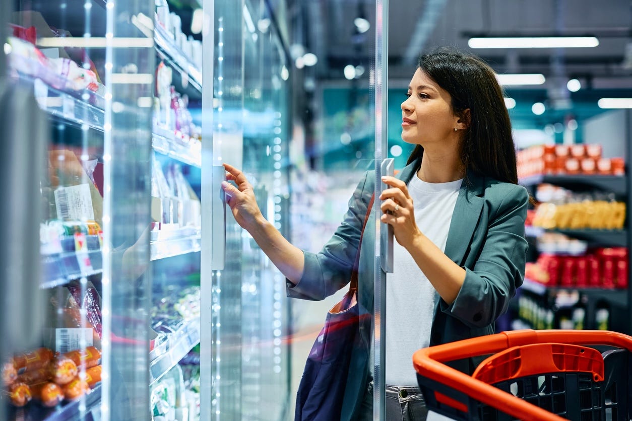 woman shopping in grocery store refrigerator aisle