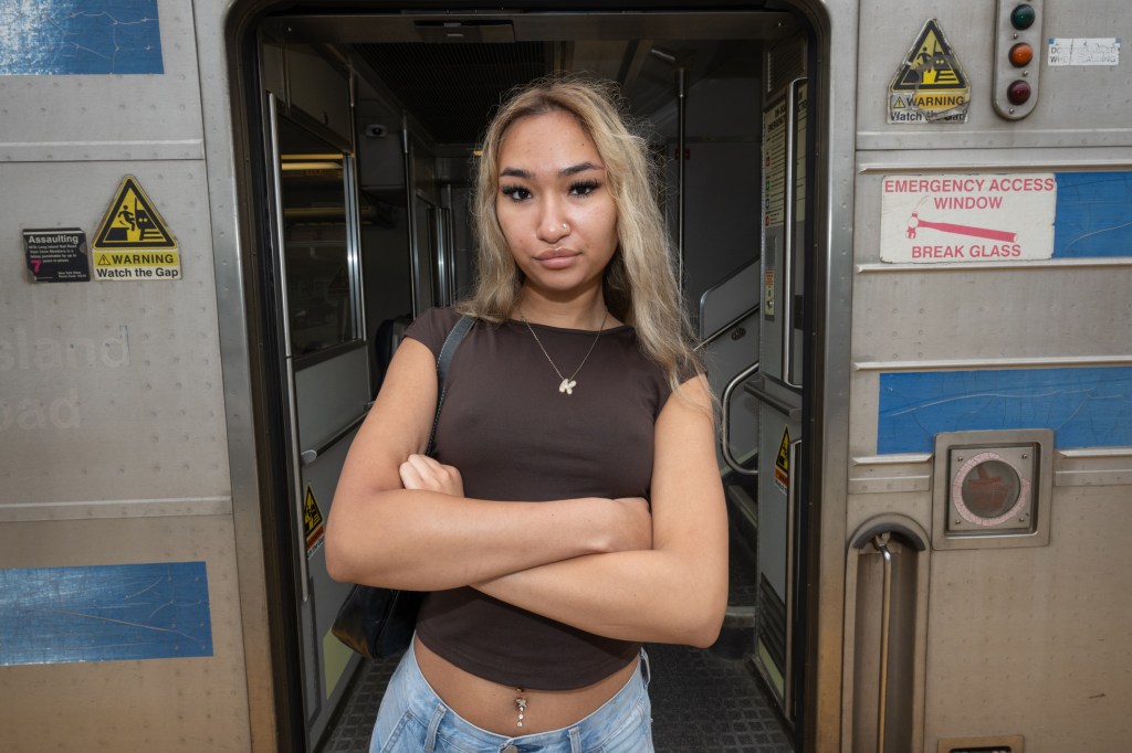 Kaylin Morales posing with her arms crossed in front of a long island railroad train