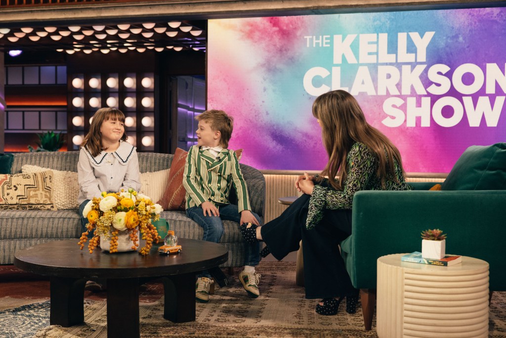 River Rose Blackstock in a cream blouse with Peter Pan collar and jeans, Remy Blackstock in a green striped blazer and jeans, Kelly Clarkson in a green floral top and black pants.