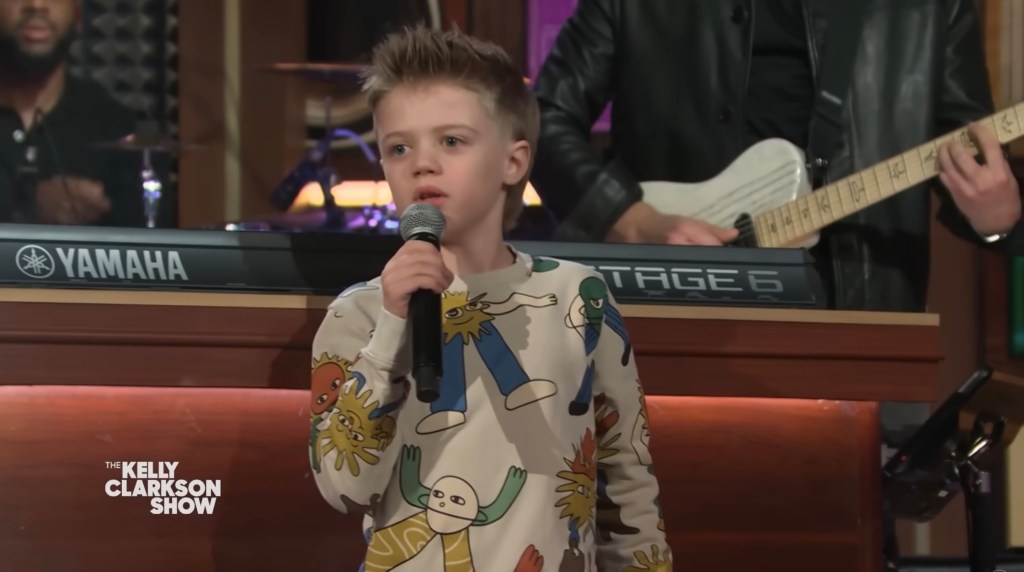 Remy Blackstock, holding a microphone, wearing a top with cartoons.