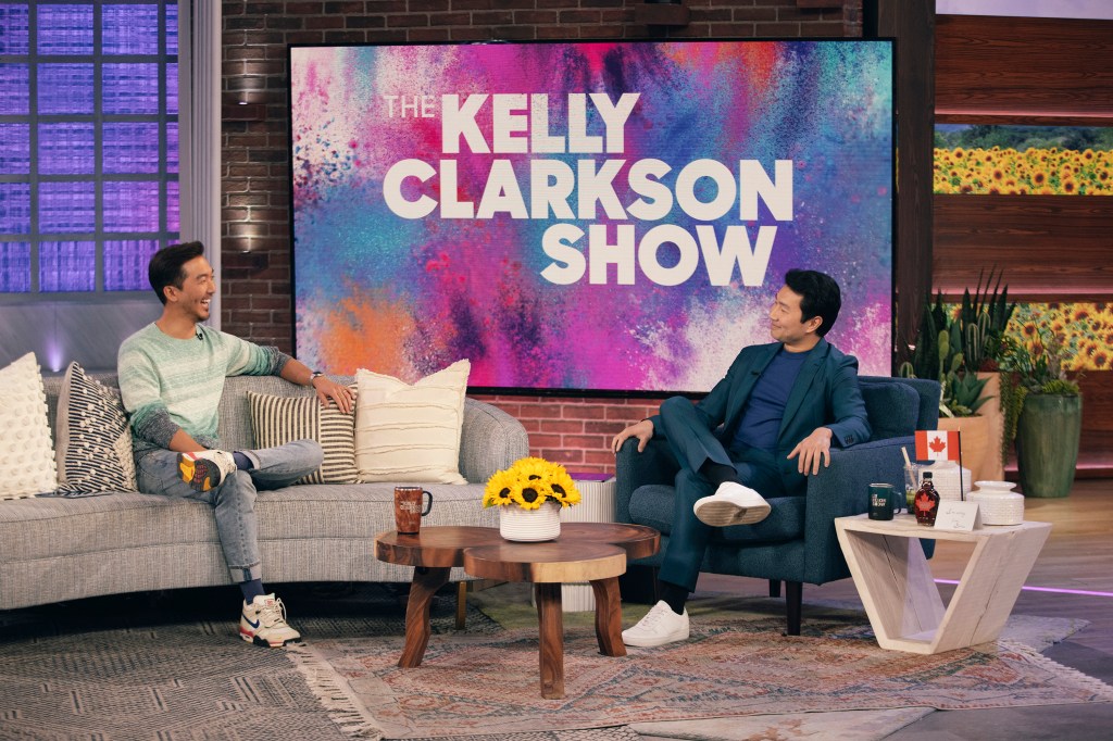 Simu Liu in a blue suit, blue top and white sneakers, Jason Y. Lee in a gray striped sweater. grey jeans and sneakers.