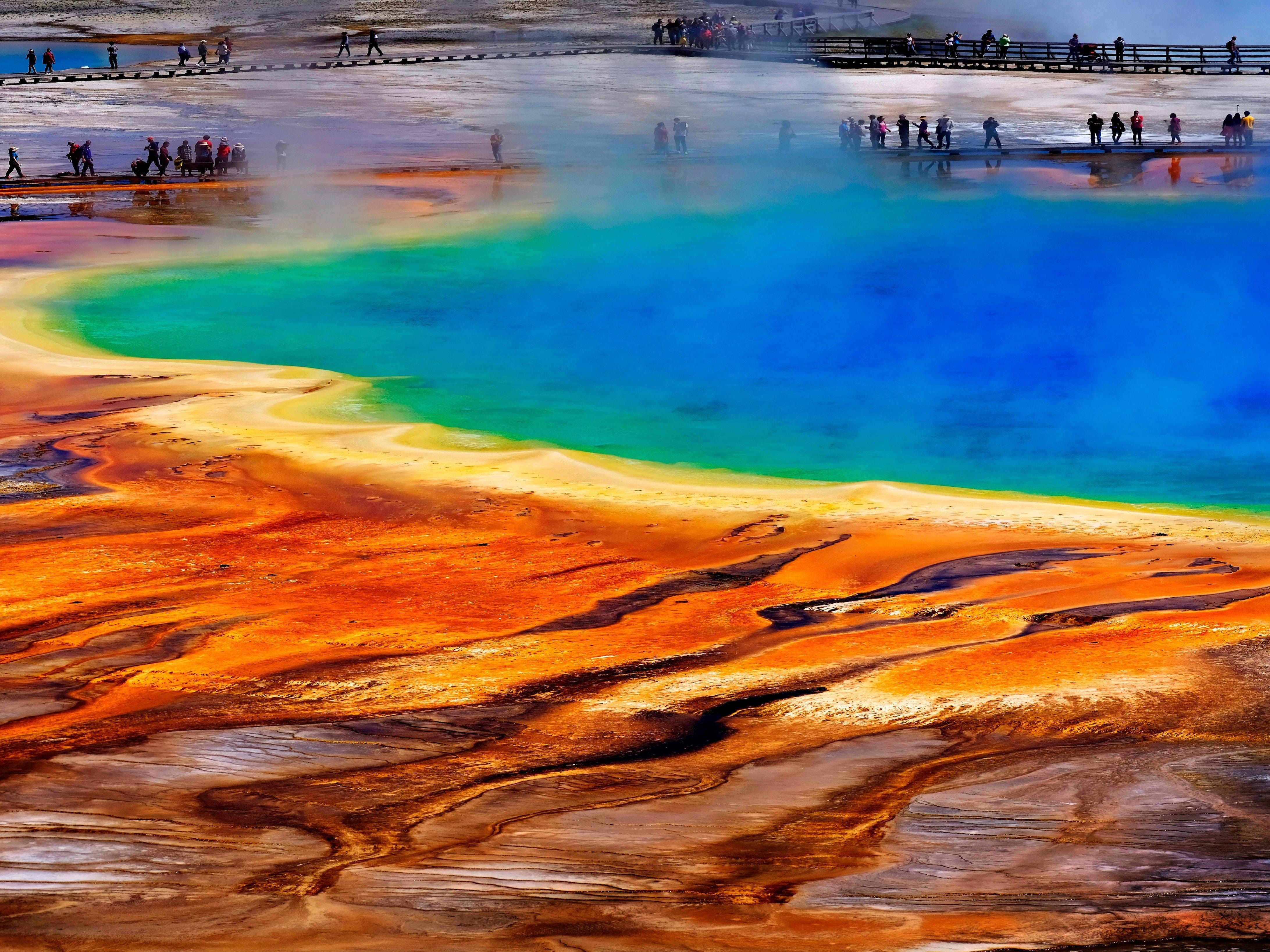 Grand Prismatic Spring in Yellowstone National Park with tourists viewing the natural scene.