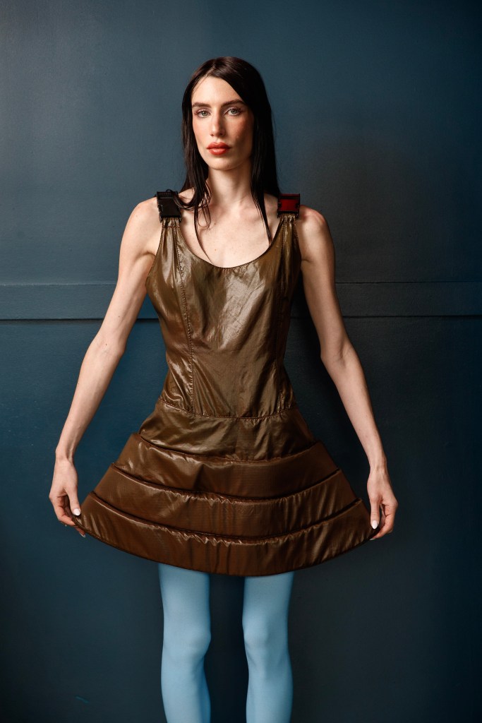 Georgia McCann stands and poses in a bronze dress and teal tights. 