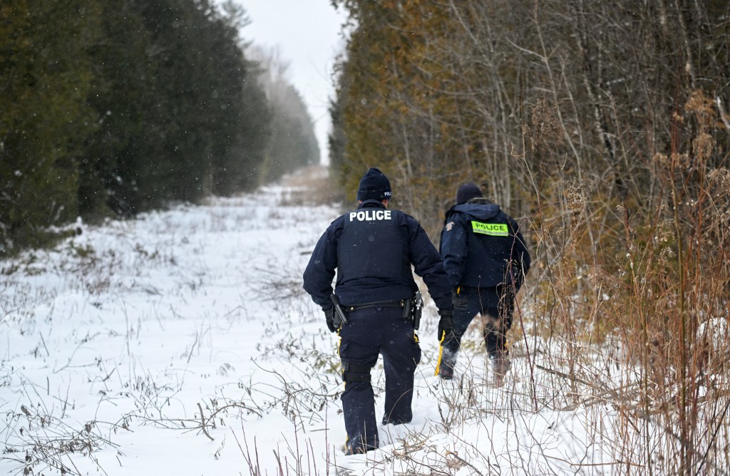 Royal Canadian Mounted Police officers patrolling a wooded area on the Canada-US border in Saint-Bernard-de-Lacolle, Quebec, Canada