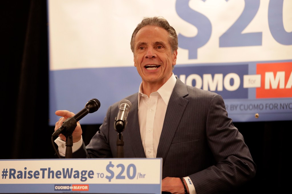 Andrew Cuomo speaking at a podium with a microphone