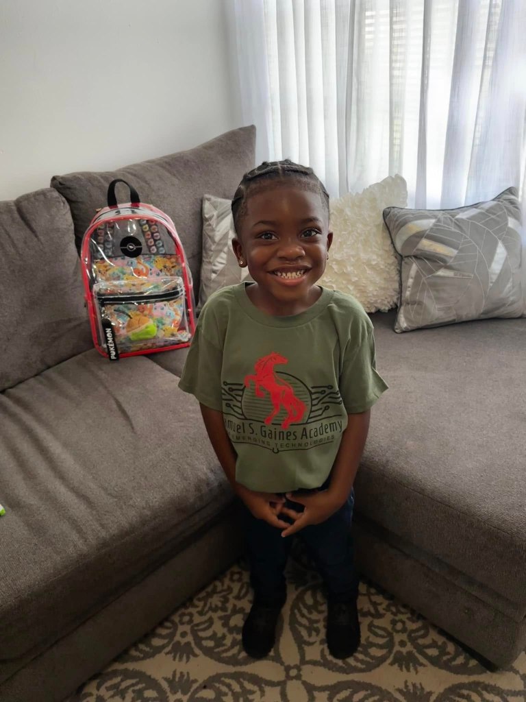 Ra'myl Pierre, 6, was found dead in his bed on Friday -- 12 days after they suspect he was killed.He is seen here smiling at the camera with his hands in front of him, wearing a gaines academy shirt and with a clear backpack on a couch behind him
