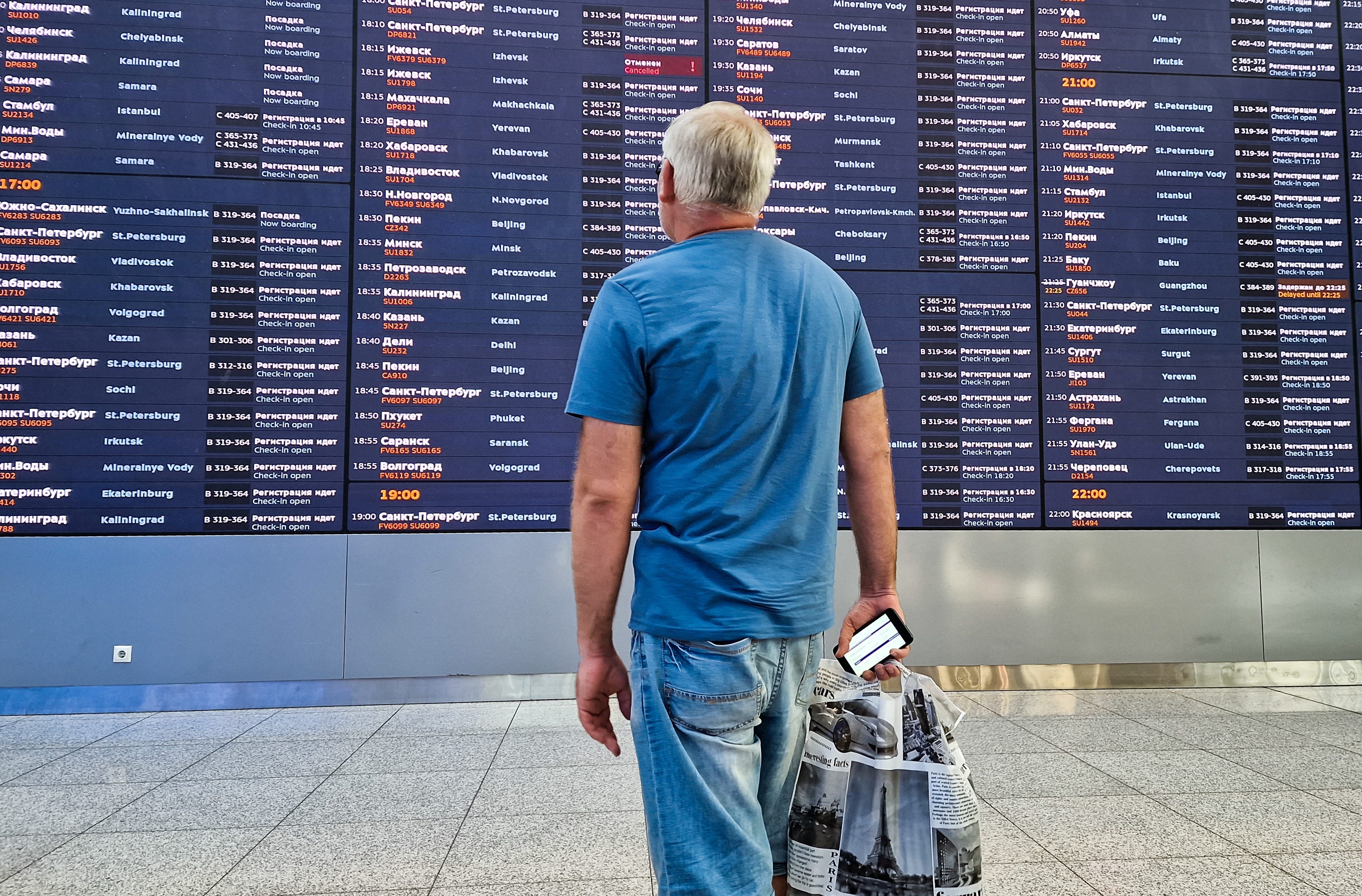A man looks at a flight information board at a terminal of the Sheremetyevo International Airport outside Moscow.