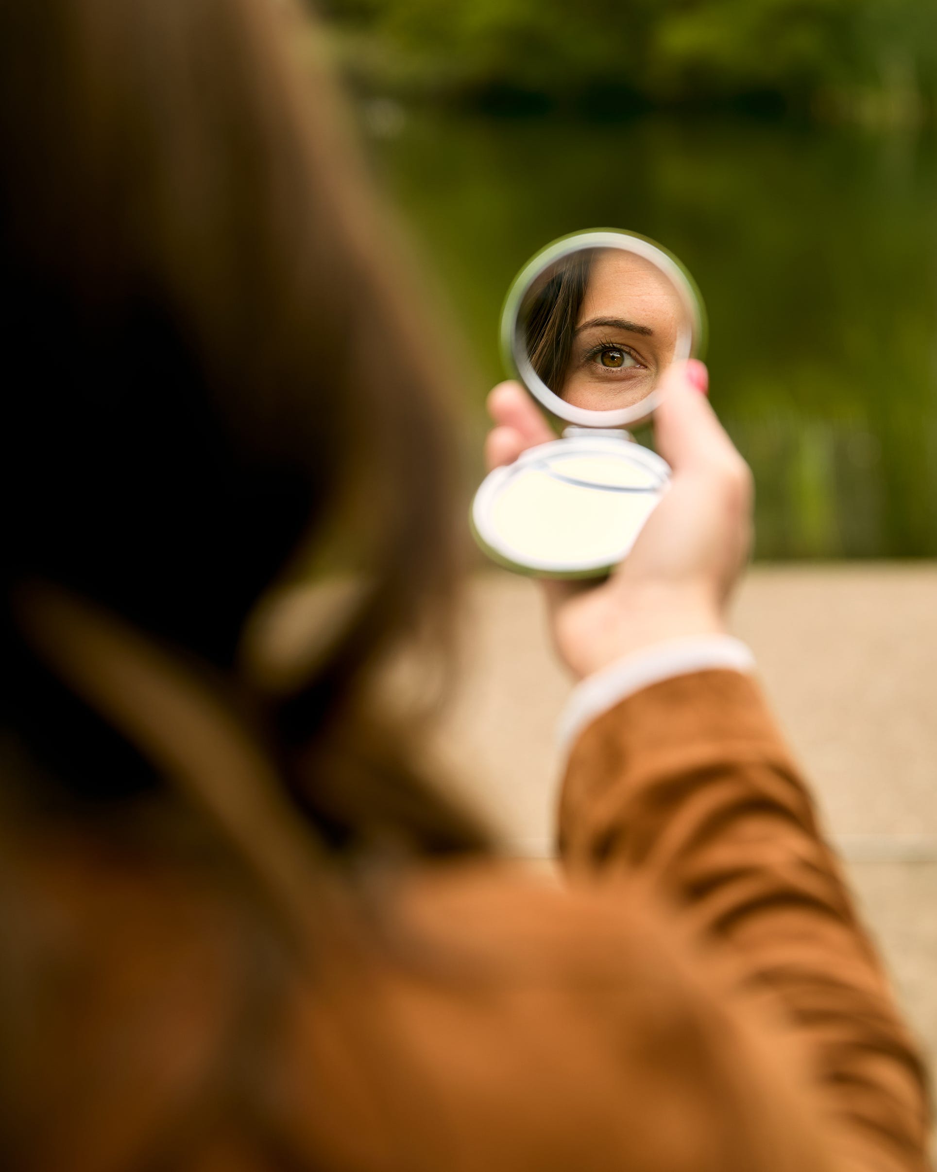 A woman looking into a compact mirror.
