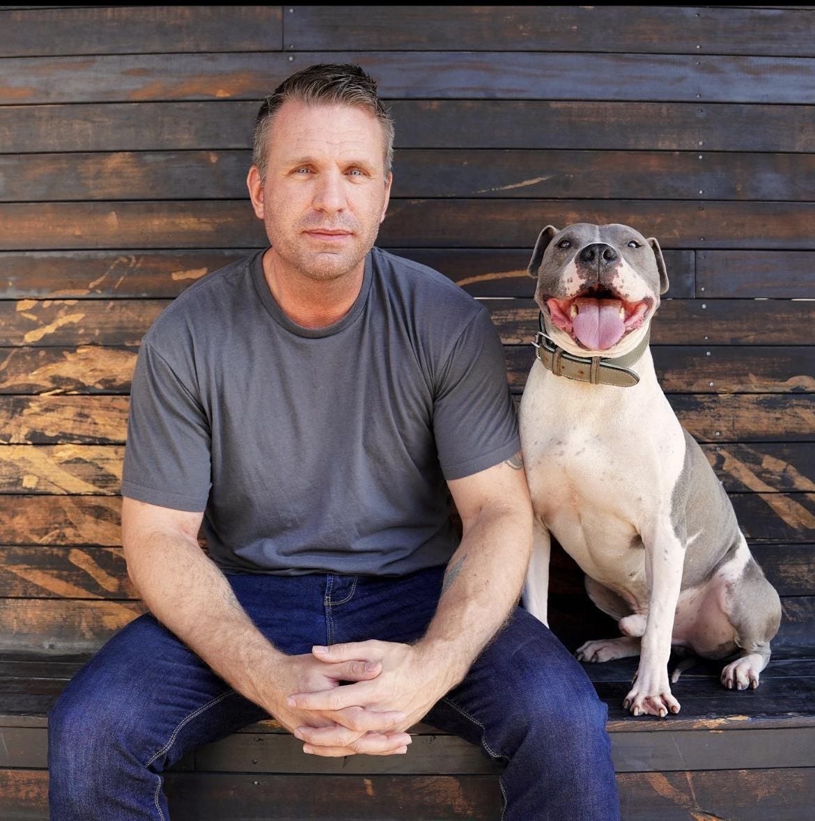 man sitting on a wooden bench next to a dog