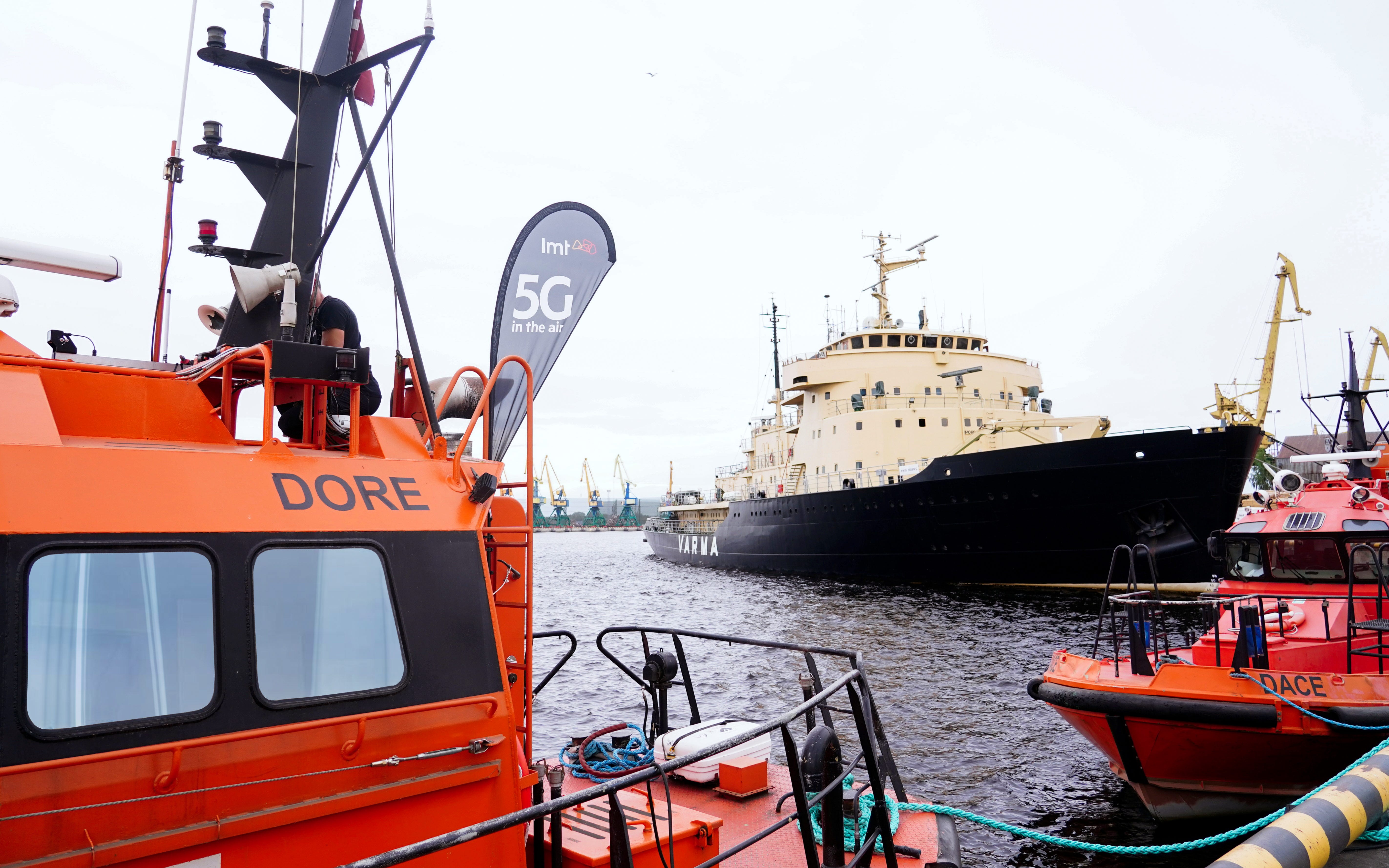 Ships docked in the Freeport of Riga, with one displaying a 5G flag