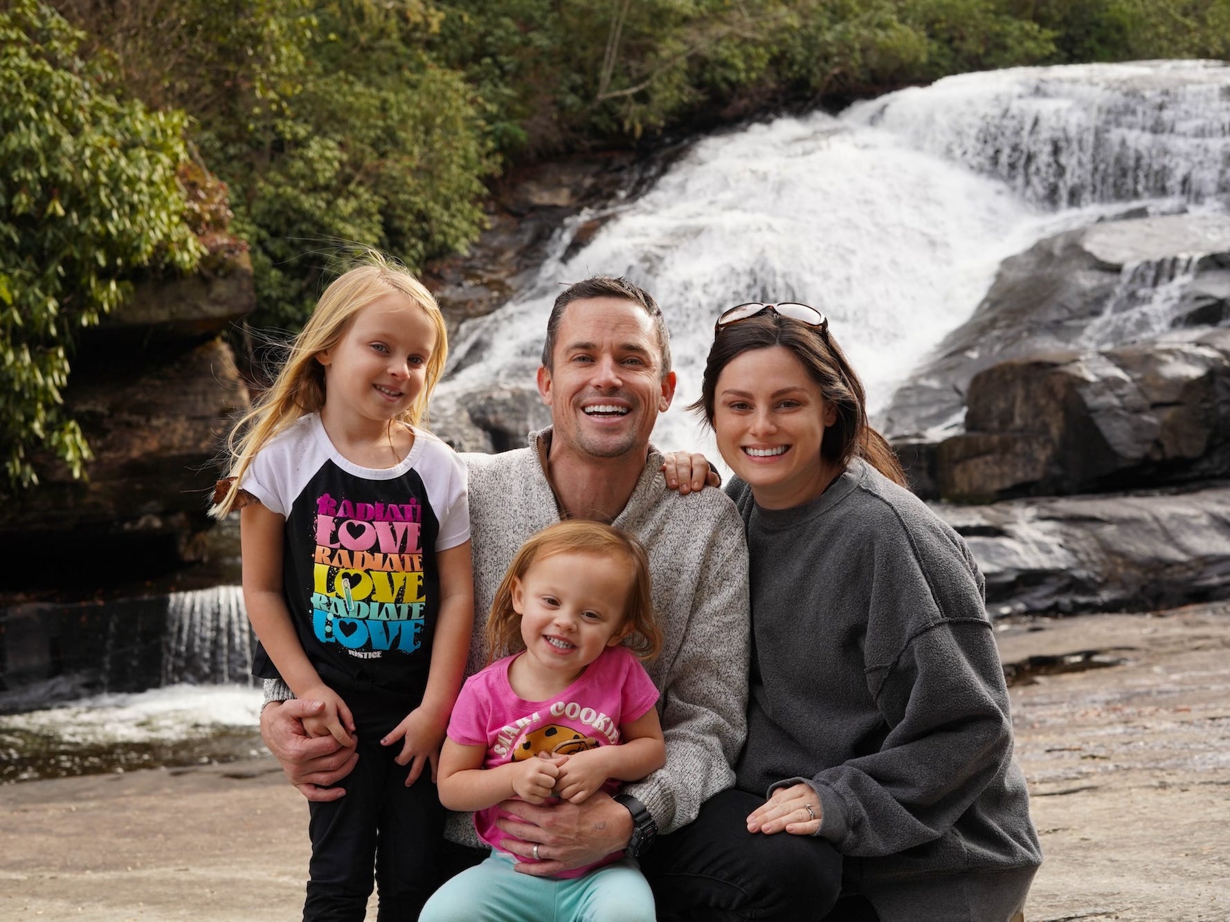 A family poses for a photo in front of a waterfall.