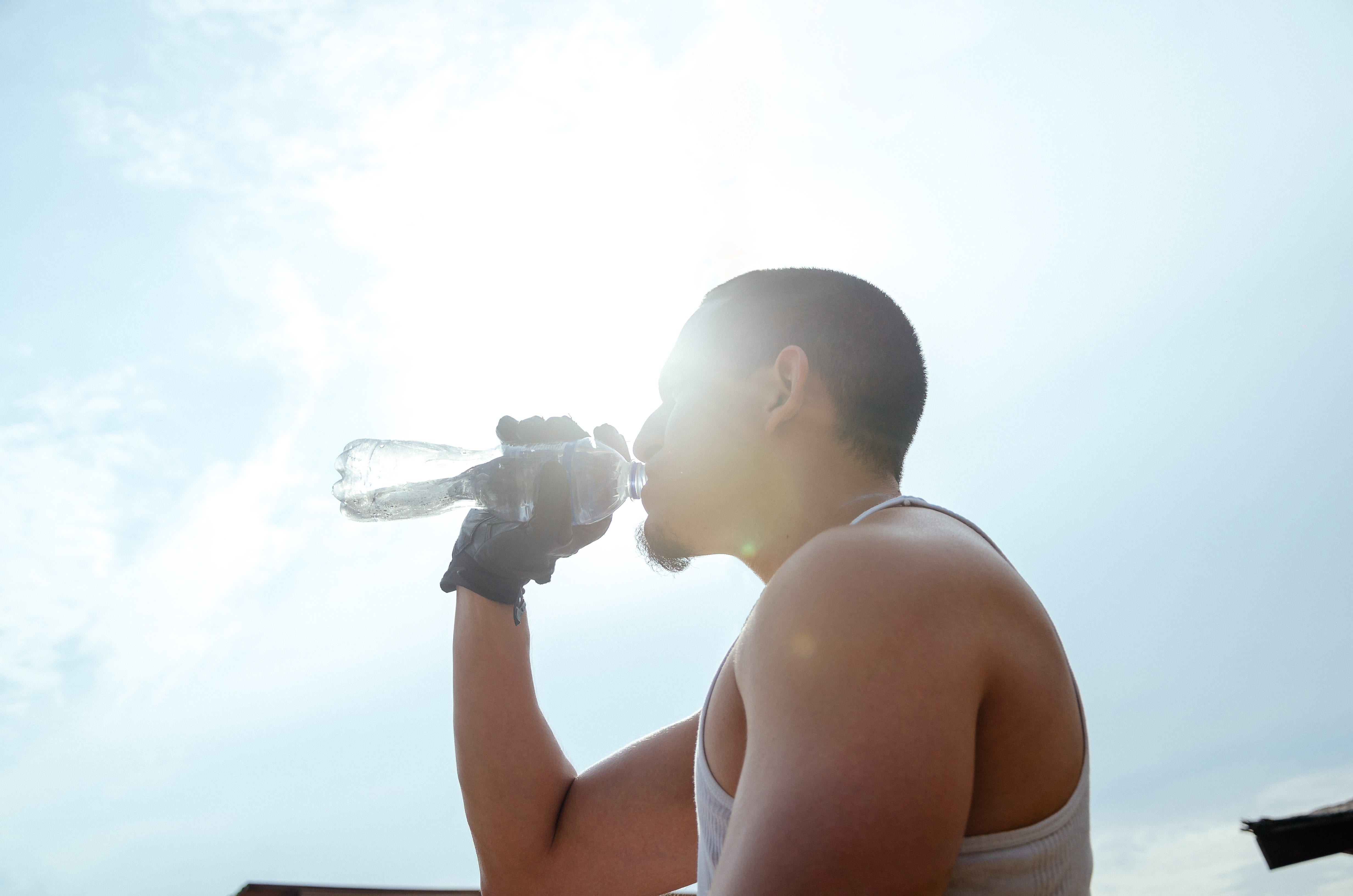 a close up image of an athlete backlit by the sun drinking water