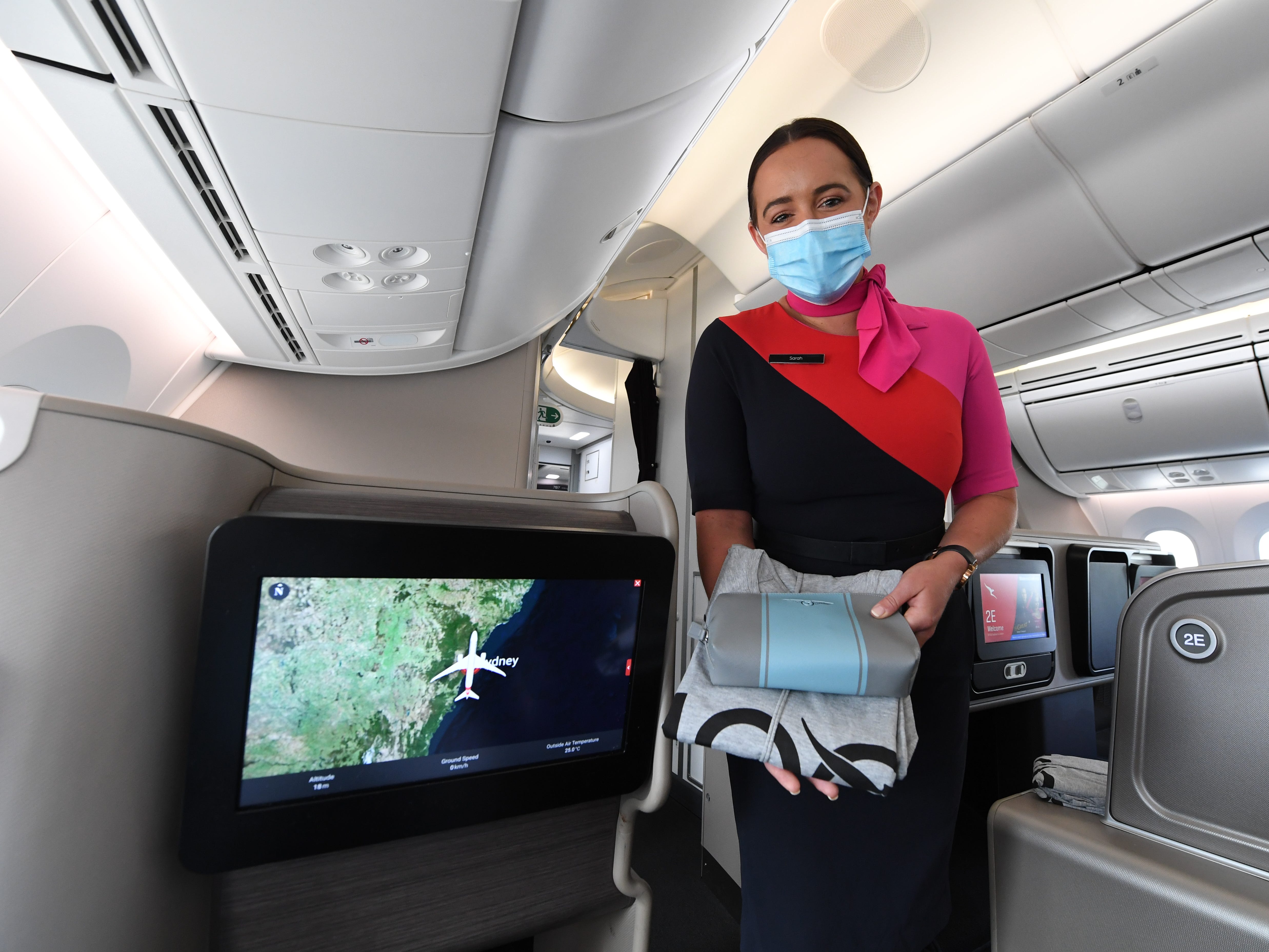 A Qantas flight attendant offers a passenger pajamas.