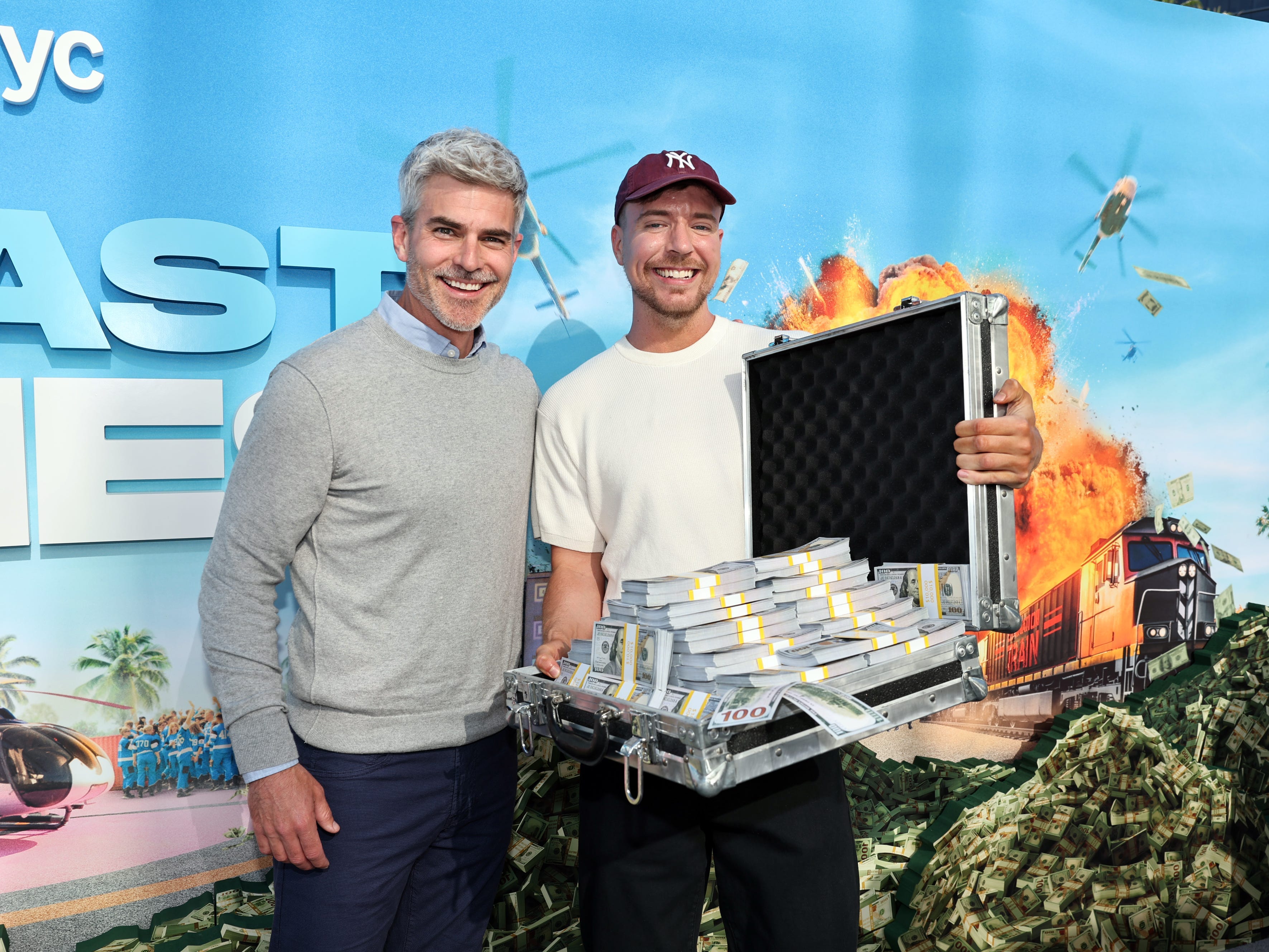 Beast Games winner Jeffrey Randall Allen and MrBeast stand on the red carpet of a screening event, holding up a briefcase full of money.