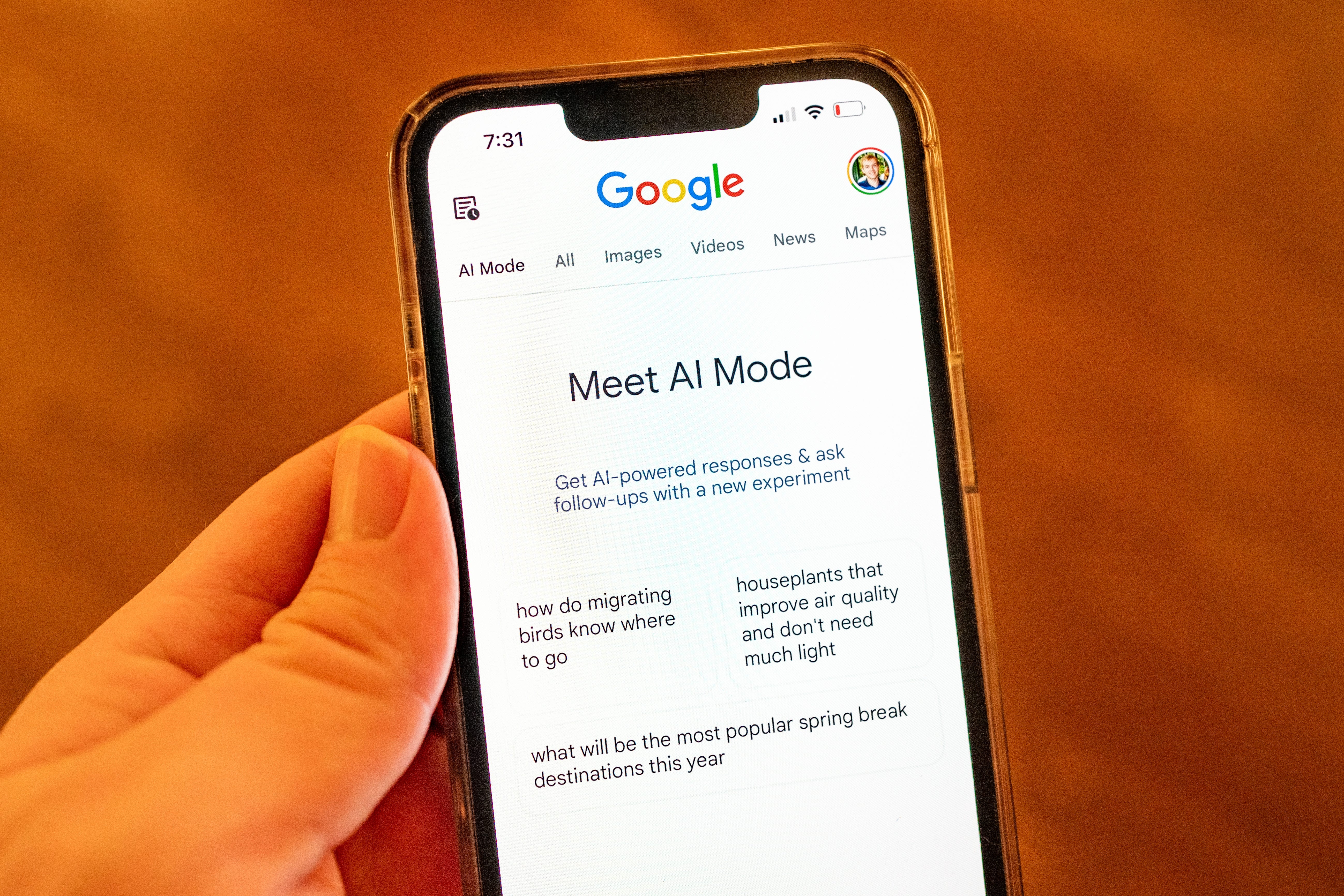 A hand holds a phone showing Google AI mode
