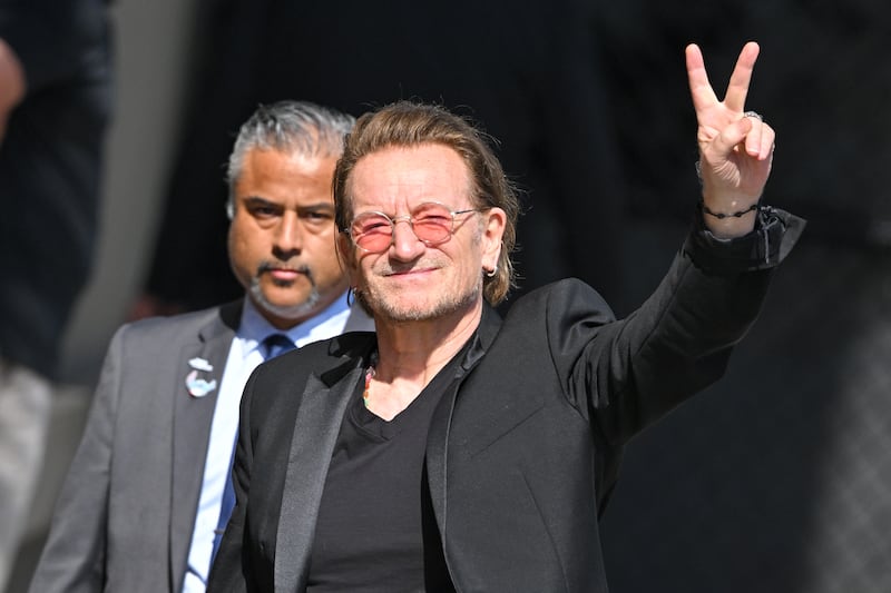 Bono holding a peace sign with fingers