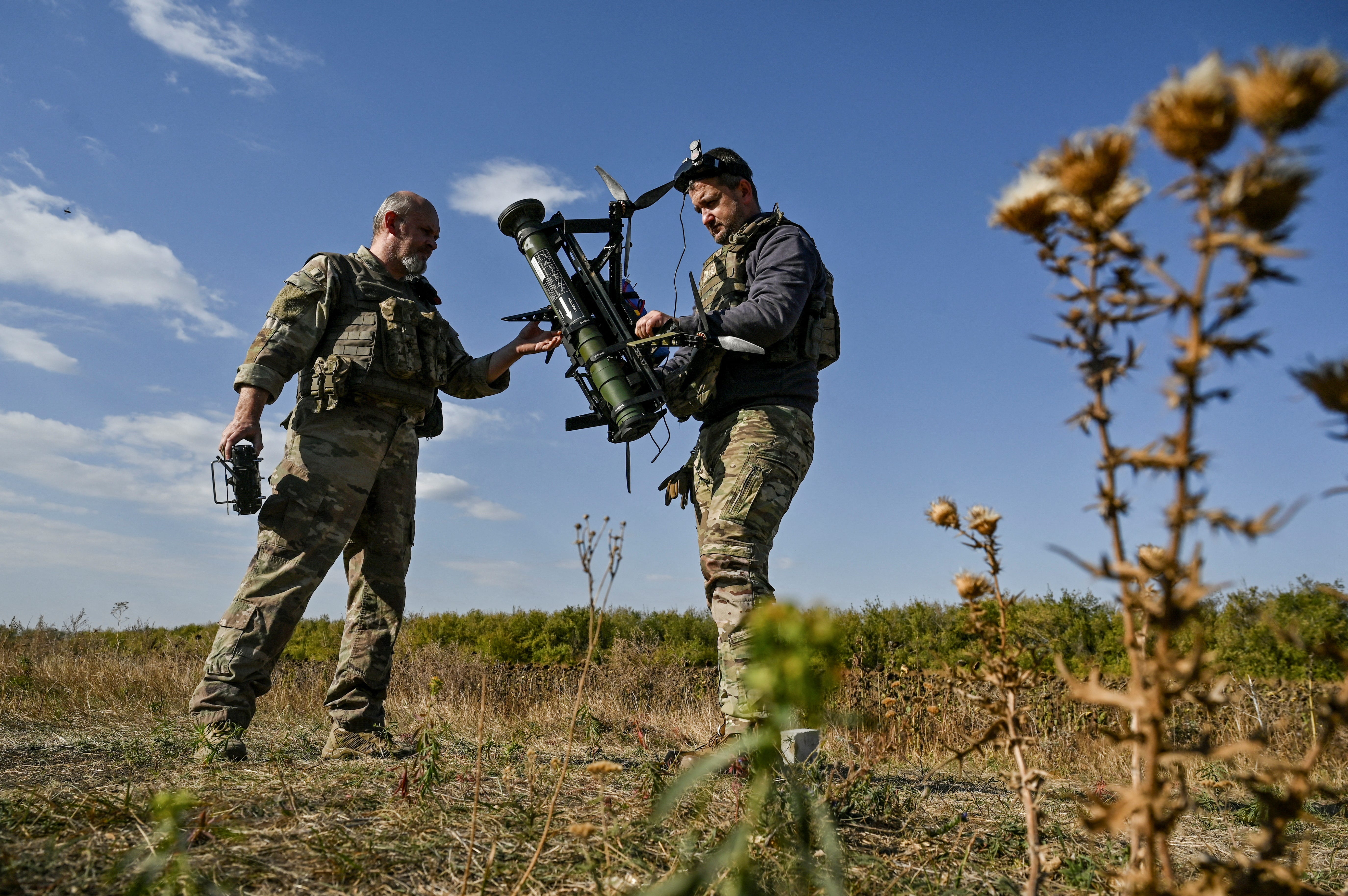 Two Ukrainian soldiers prepare a drone-mounted grenade launcher for testing.