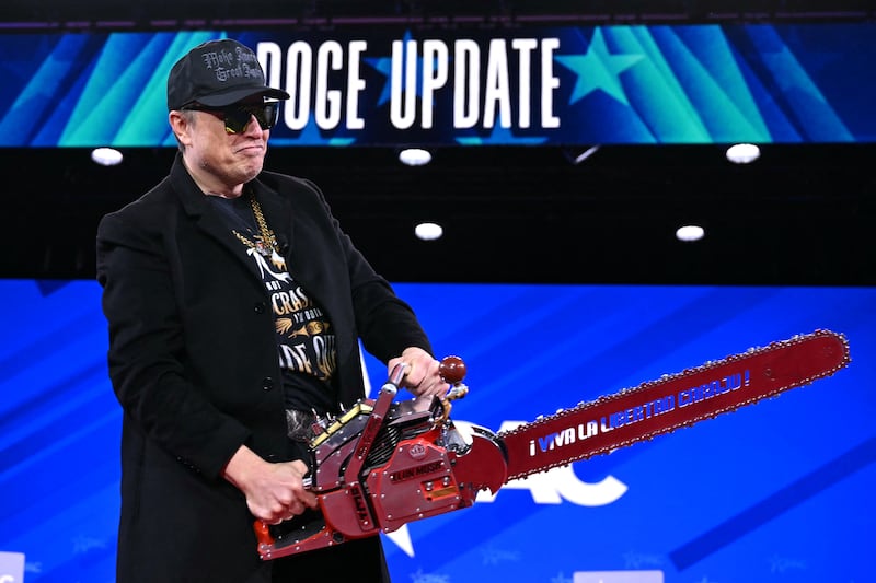 Elon Musk holds a chainsaw reading