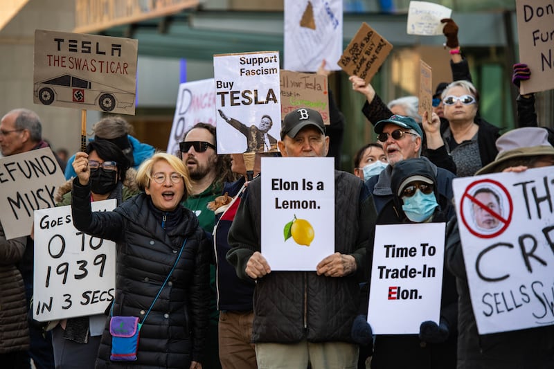 Protesters hold signs and sing chants during a protest against Elon Musk and his Tesla car company outside the Tesla dealership in Boston, Massachusetts on March 15, 2025. US President Donald Trump's senior advisor Elon Musk is leading the so-called Department of Government Efficiency (DOGE), which has cut thousands of government jobs and upended agencies, prompting numerous court challenges. (Photo by Joseph Prezioso / AFP) (Photo by JOSEPH PREZIOSO/AFP via Getty Images)
