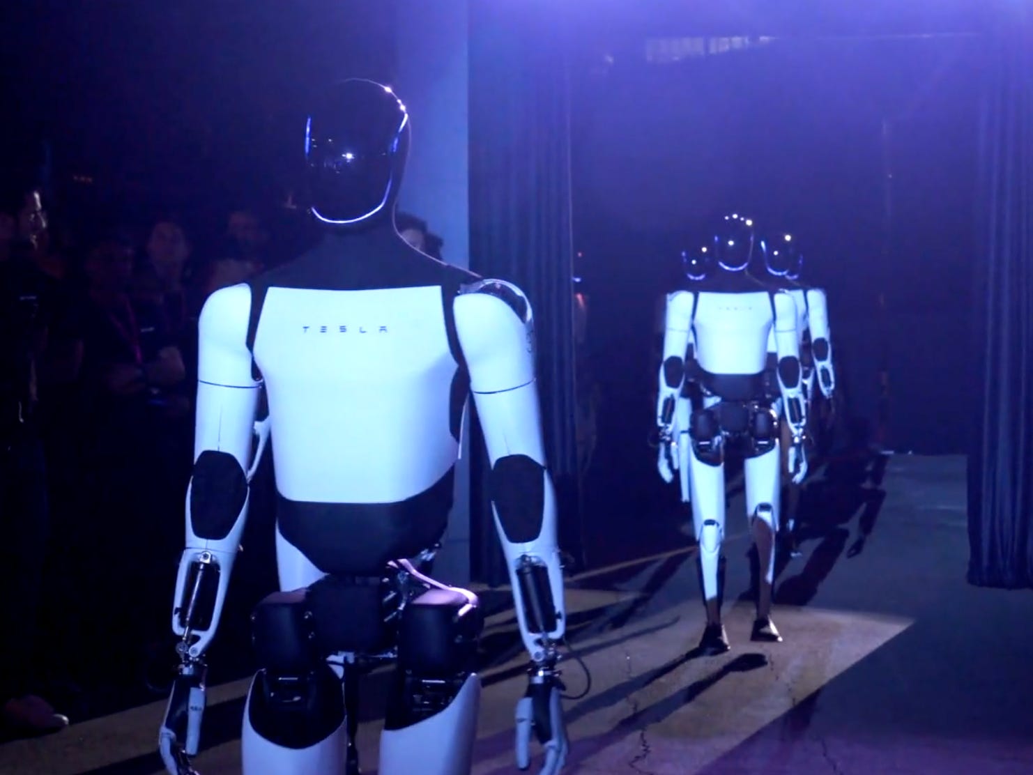 Tesla Optimus robots under a spotlight.