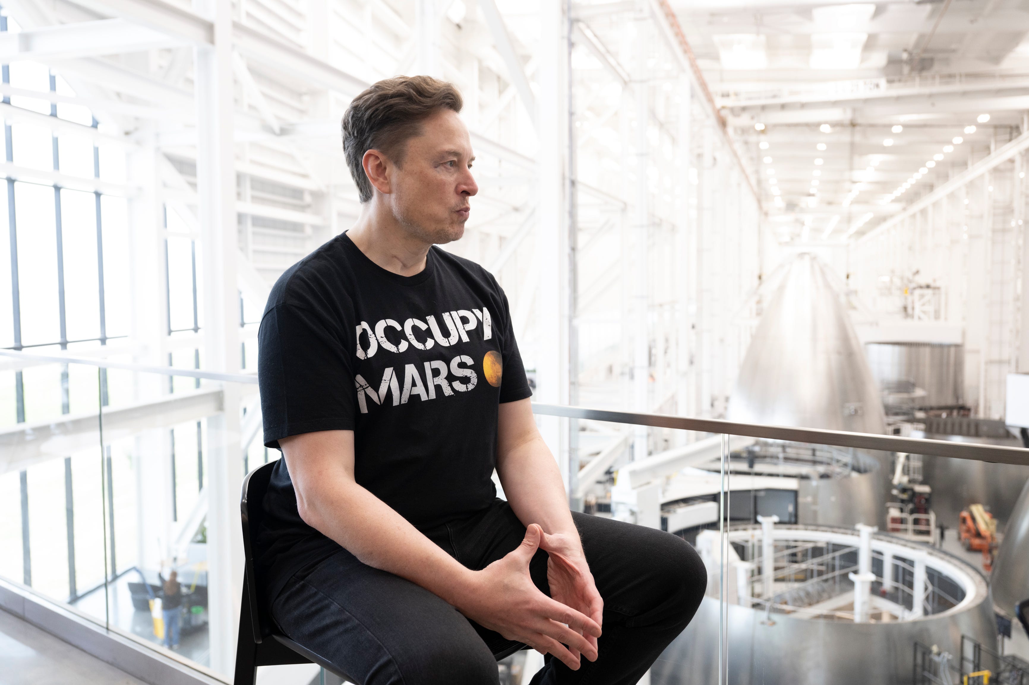 Elon Musk sitting in a chair.
