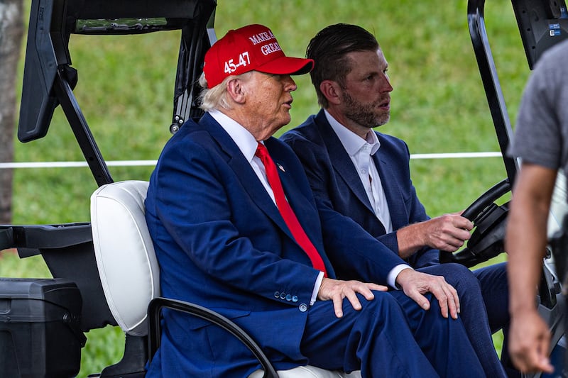 President Donald Trump and his son Eric Trump drive in a golf cart in Miami.