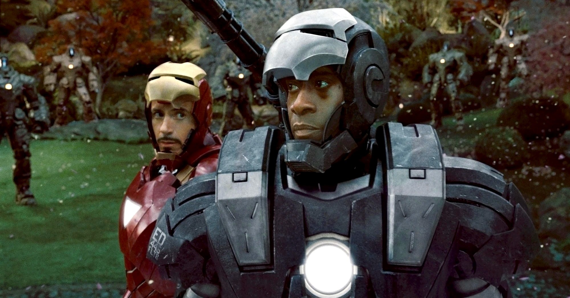 Don Cheadle’s Rhodey stands suited up as War Machine in front of a damaged Tony Stark in his Iron Man armor in Iron Man 2