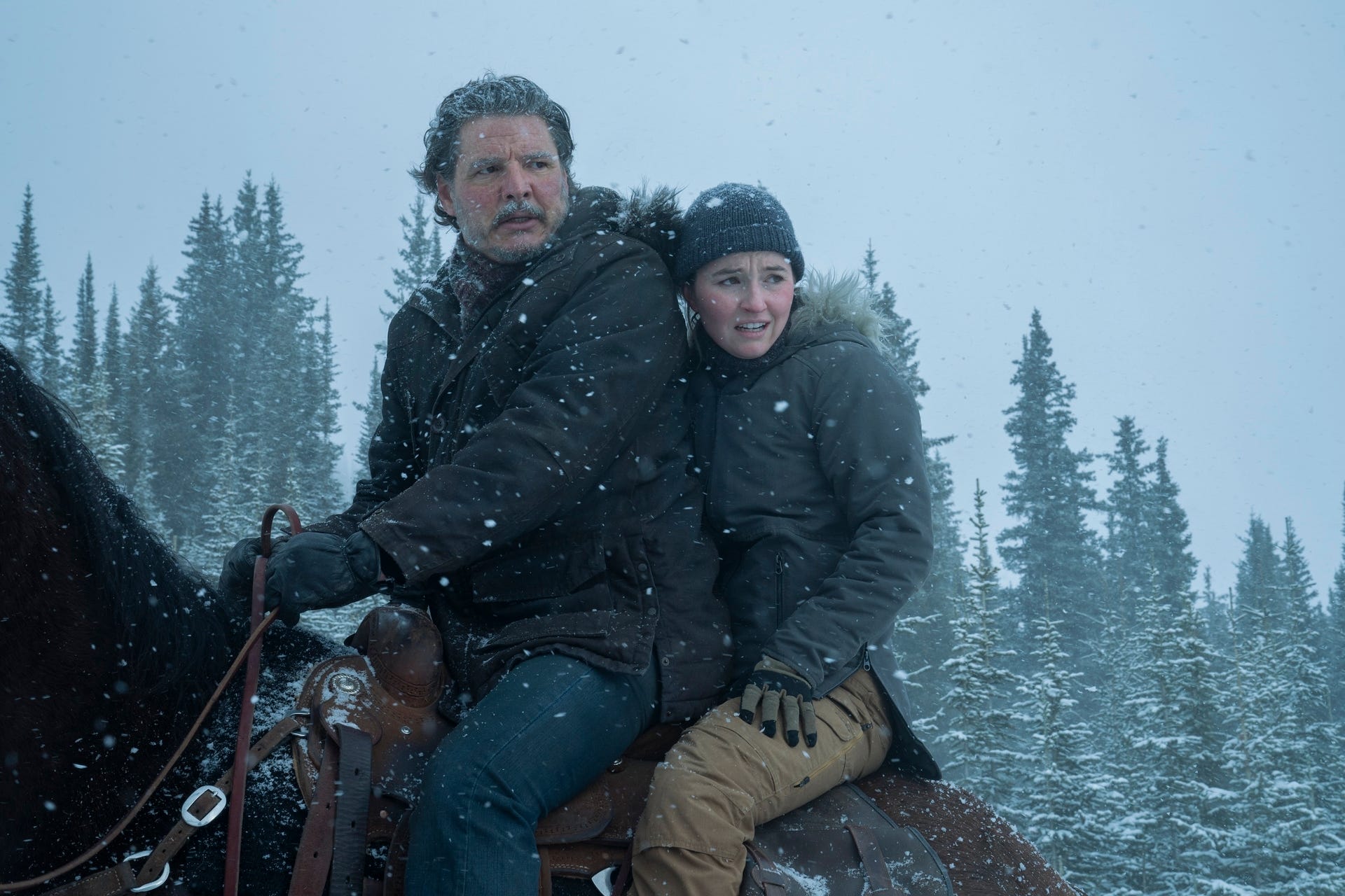 A man and woman wearing winter attire while on a horse in a scene in season two of "The Last of Us."