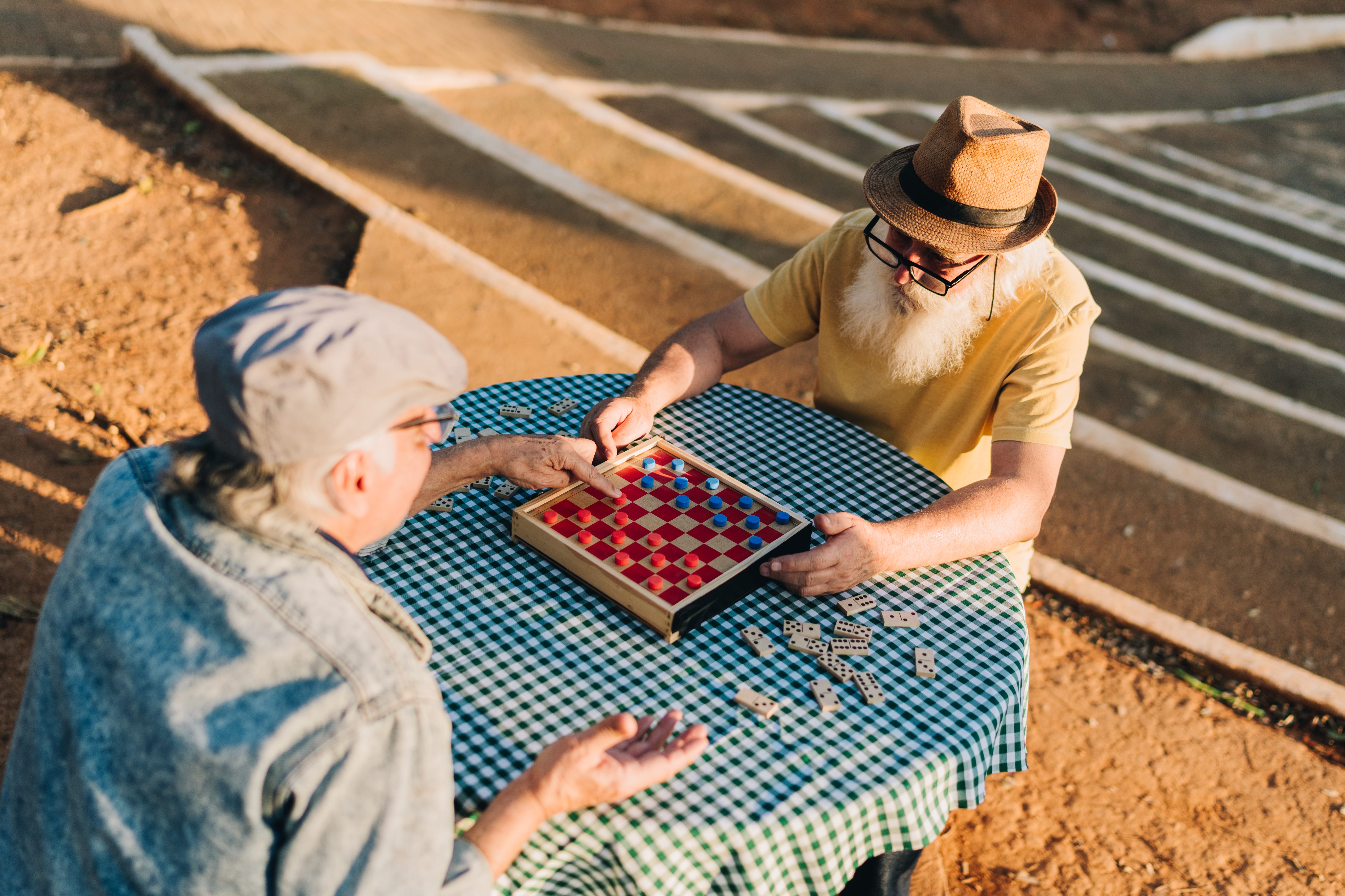 Two men playing Checkers and games in a park.