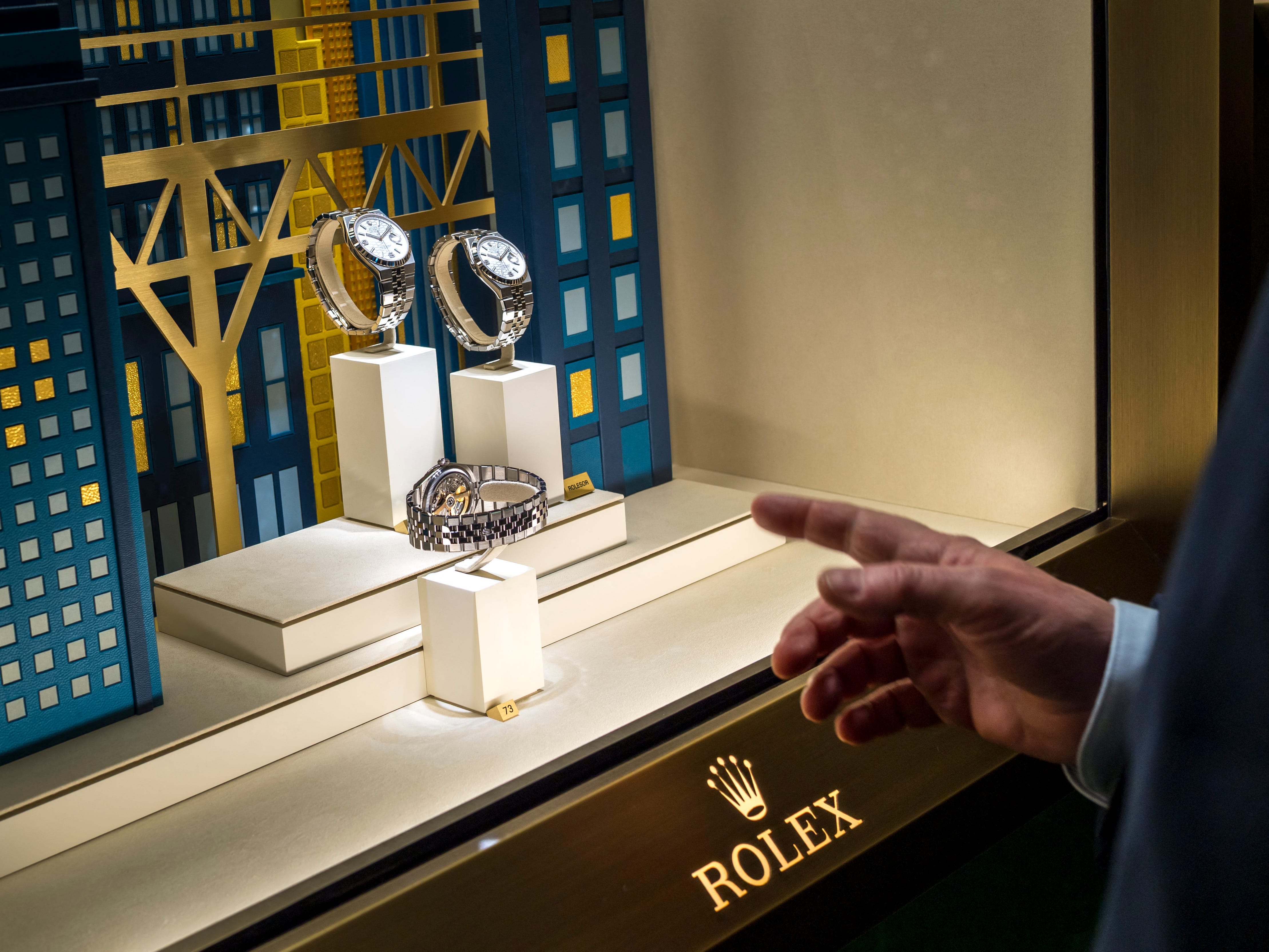 a man pointing at rolex watches in store window