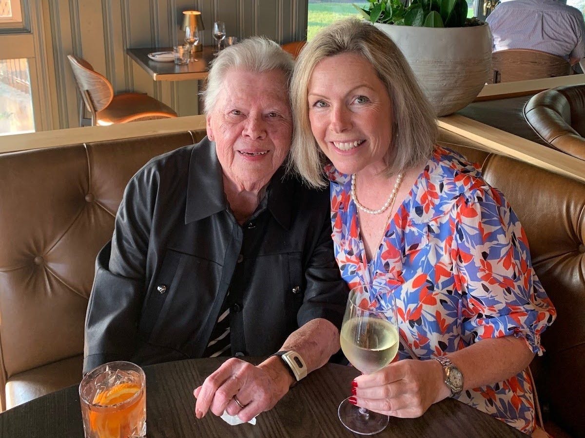 a woman poses with her mother at a table in a restaurant