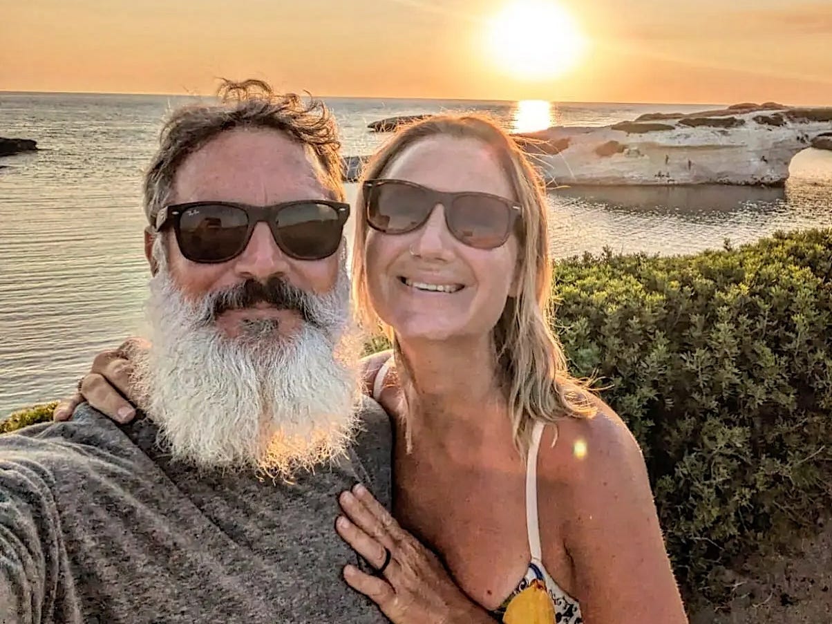 The author and her husband standing on a beach at sunset.