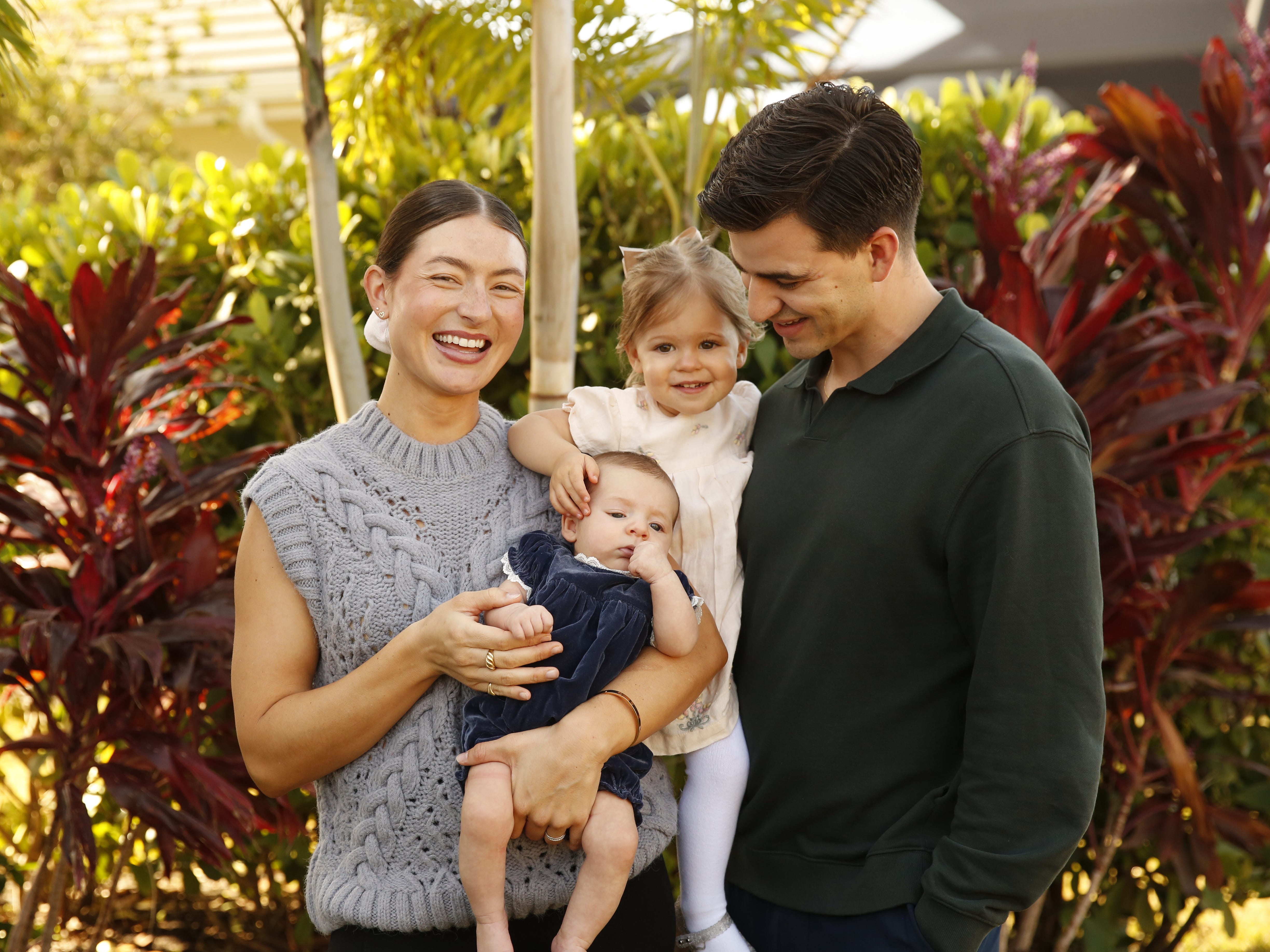 Sabel Bezet with her two kids and husband standing outside and smiling.