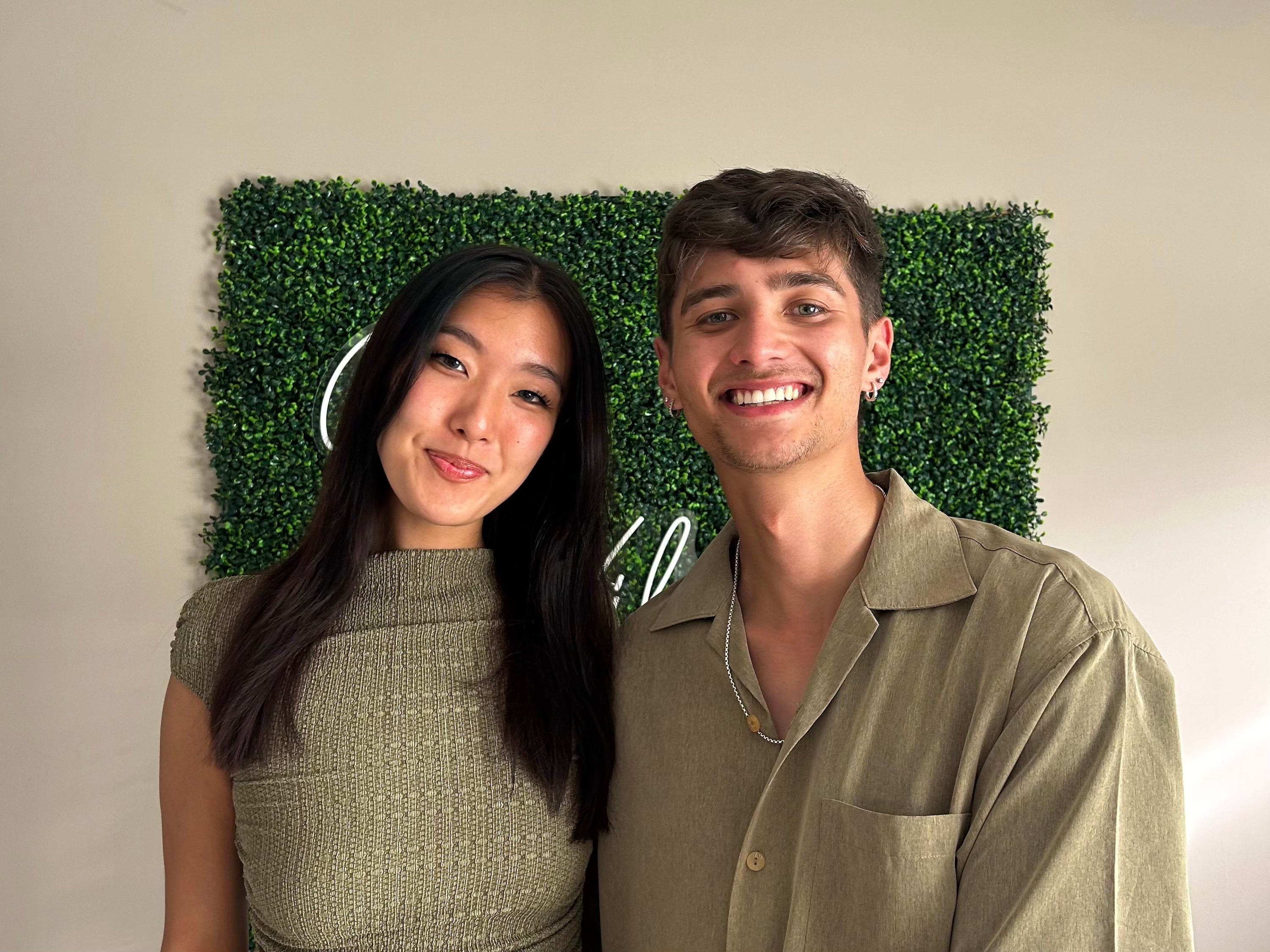 The author and her boyfriend standing in front of a wall with a green background.