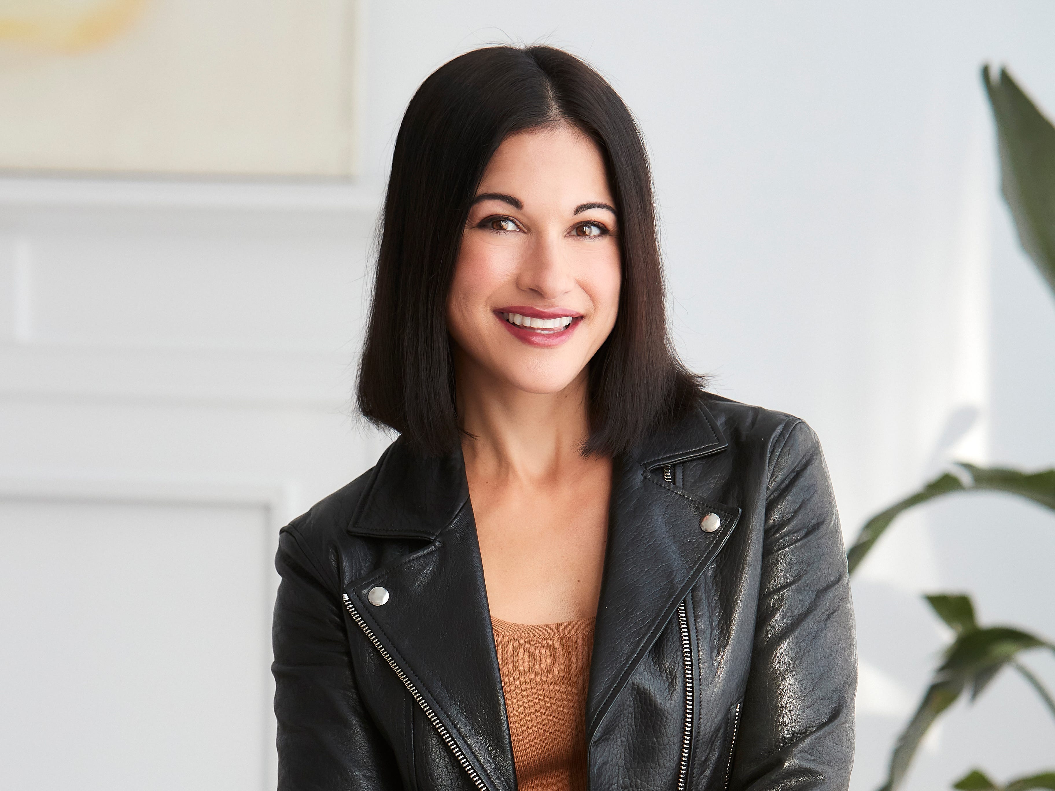 headshot of a woman in a brown dress and a leather jacket